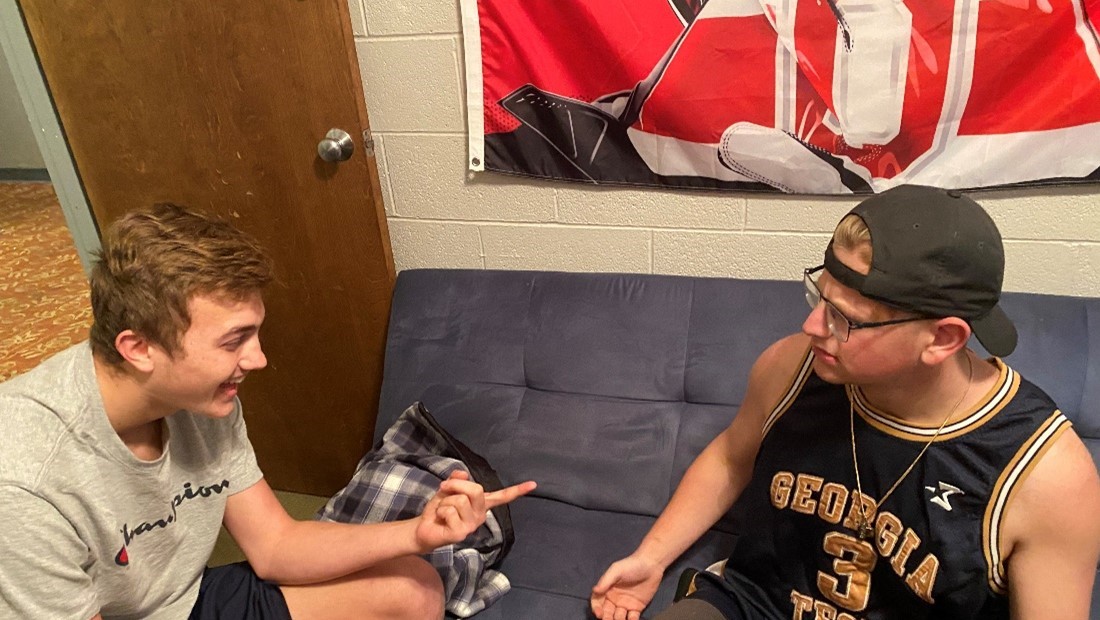 two white male college students talking in dorm room 