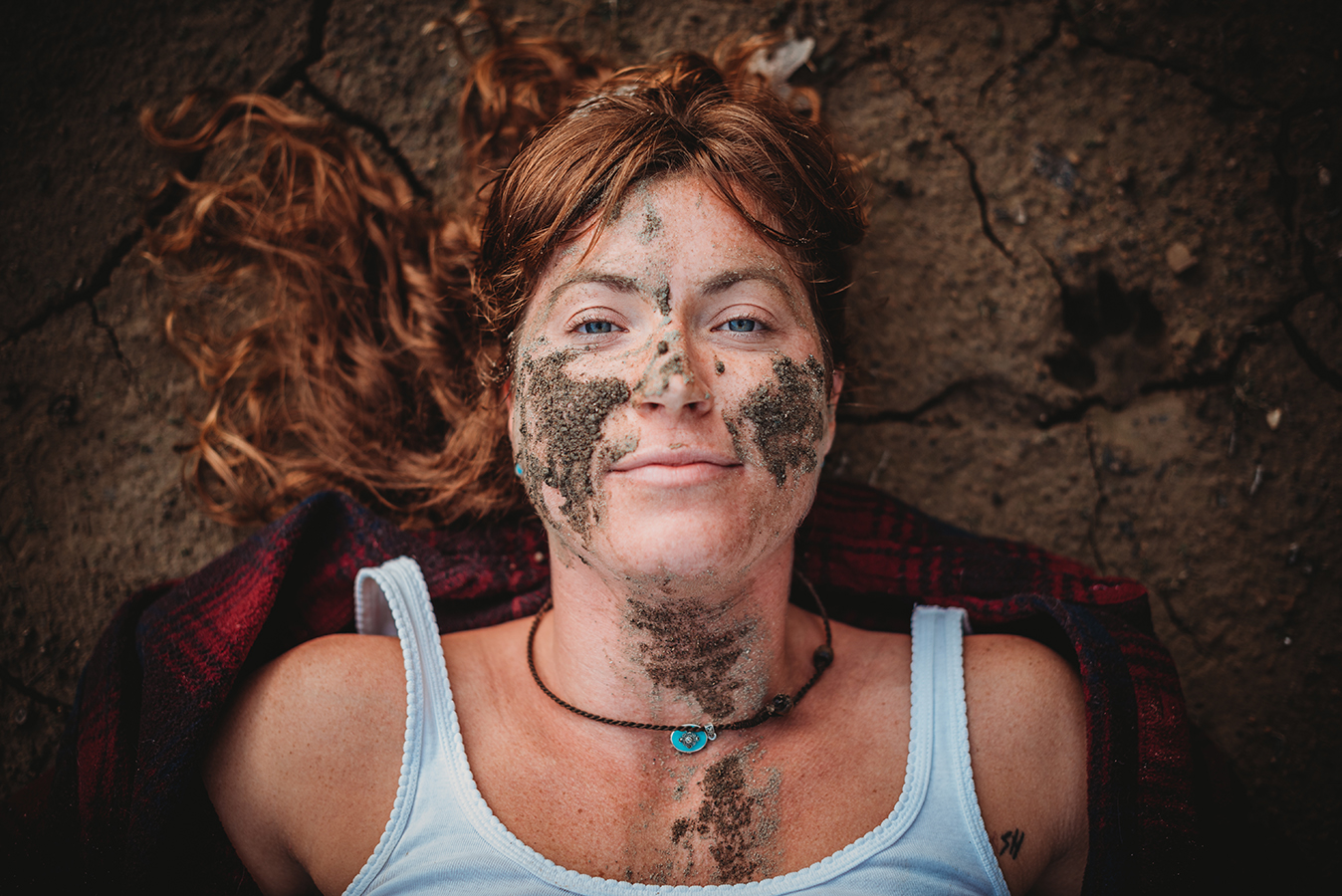 woman laying in mud smiling