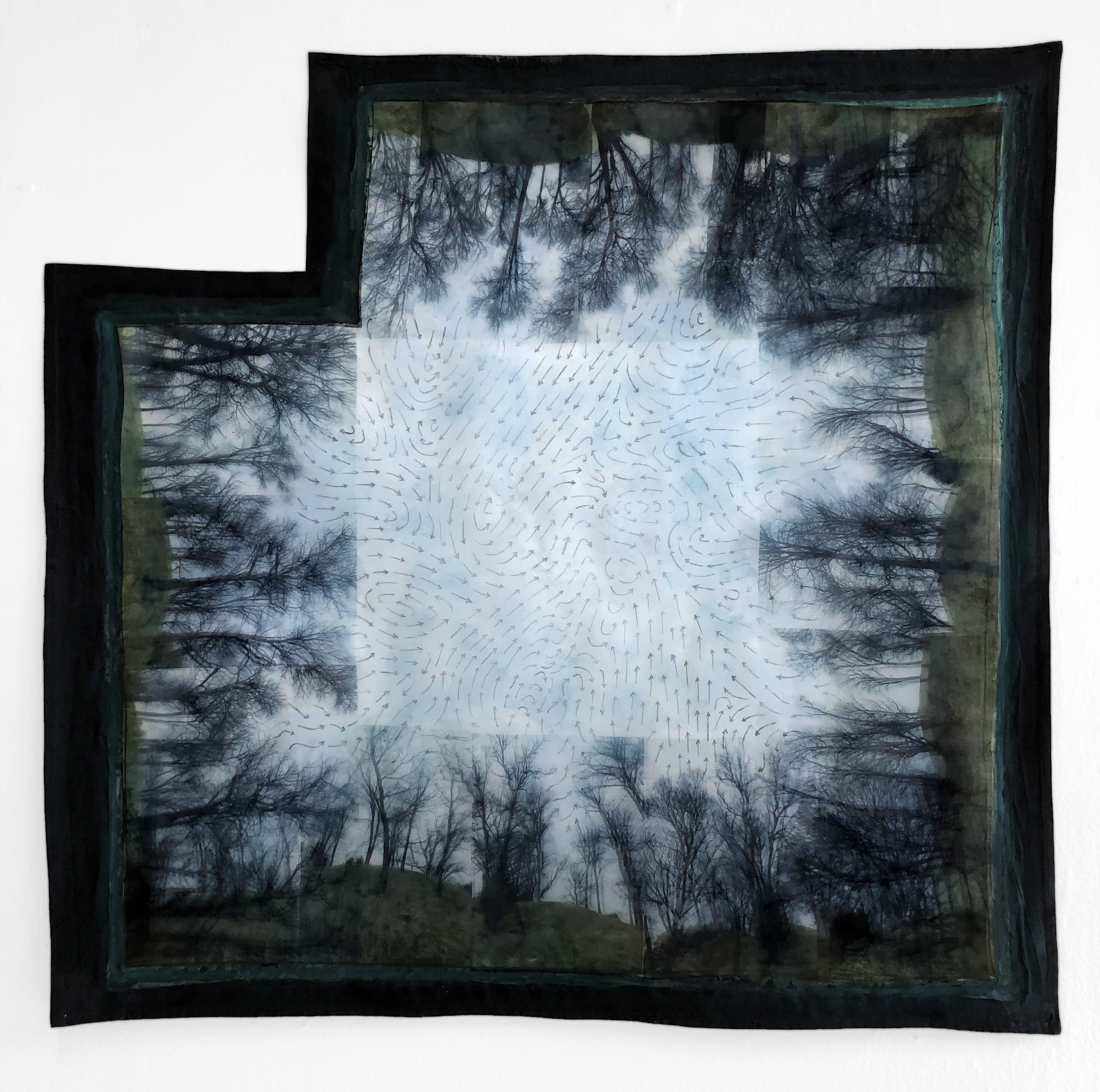 A photographic image printed on a square piece of fabric with the top left corner missing. Images around the board of the fabric of trees without leaves pointing inwards towards the center of the square. The image is all blueish gray with a black border. 