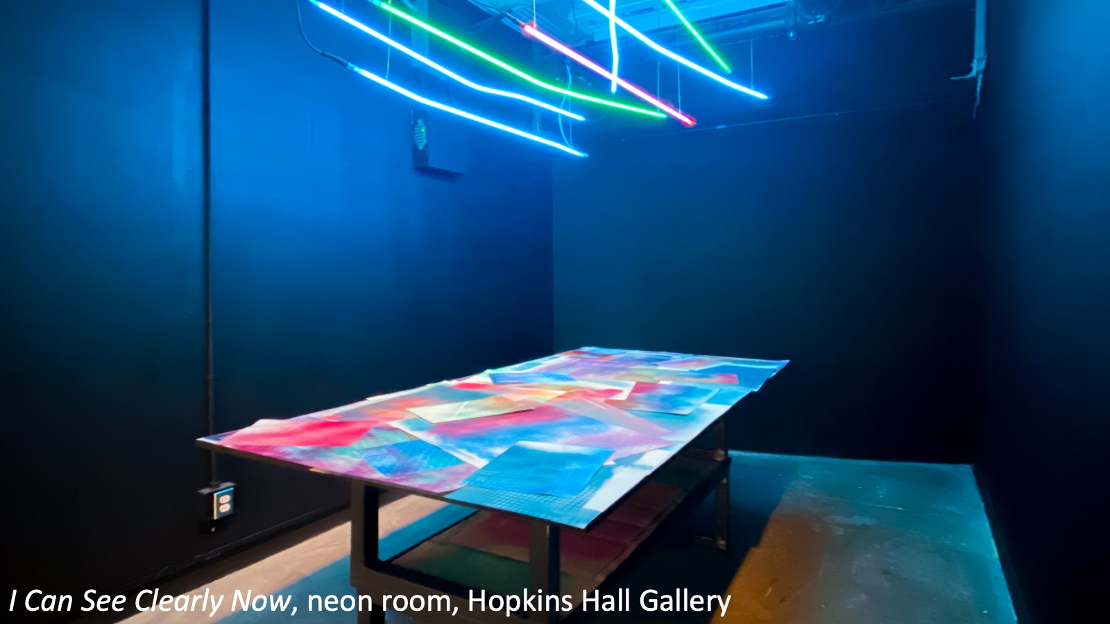 A colorful table under neon lights for the exhibition "I Can See Cleary Now."