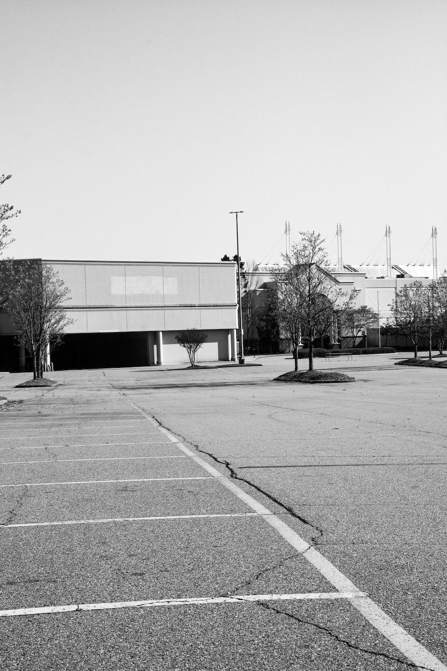 A black-and-white photo of an empty parking lot in front of a vacant store