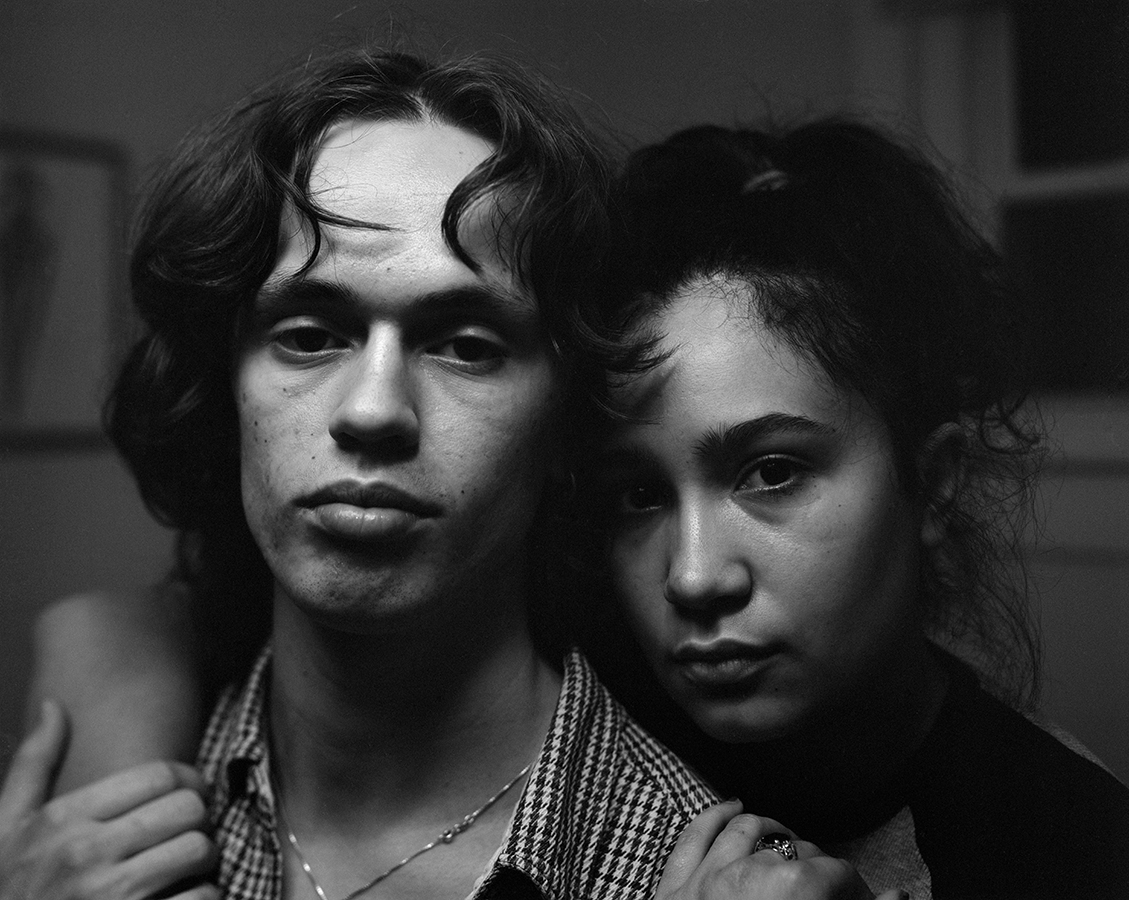 A black-and-white photo of two people holding each other close and looking at us