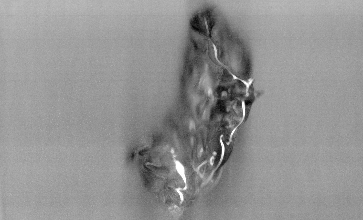 A blurry grayscale scan of a misshapen glass object