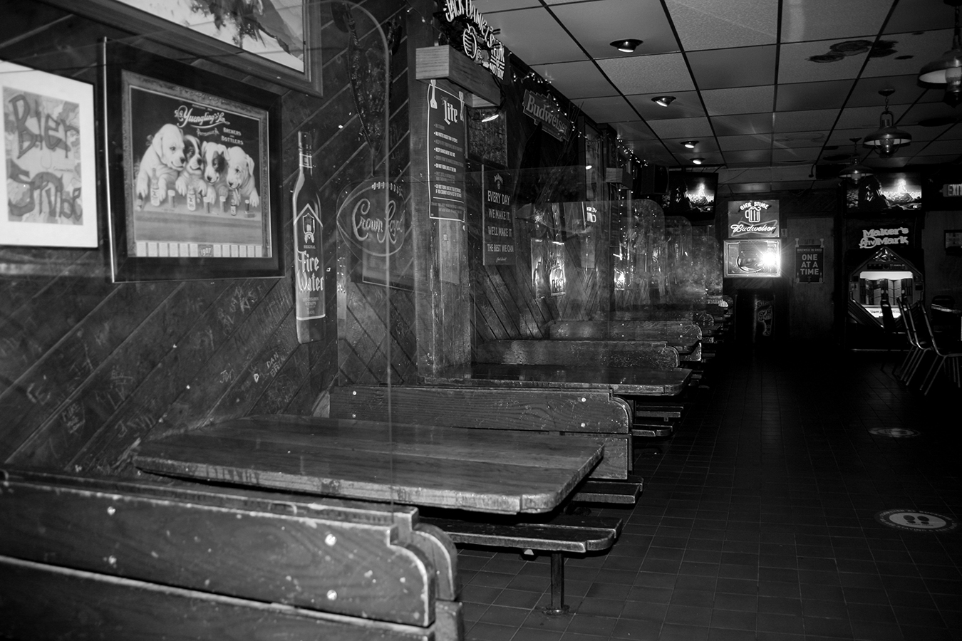 A black-and-white photo of the empty booths separated by plexiglass at the Bier Stube