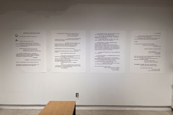 A poem is displayed on the wall of the gallery in the form of four large, white posters with black text.