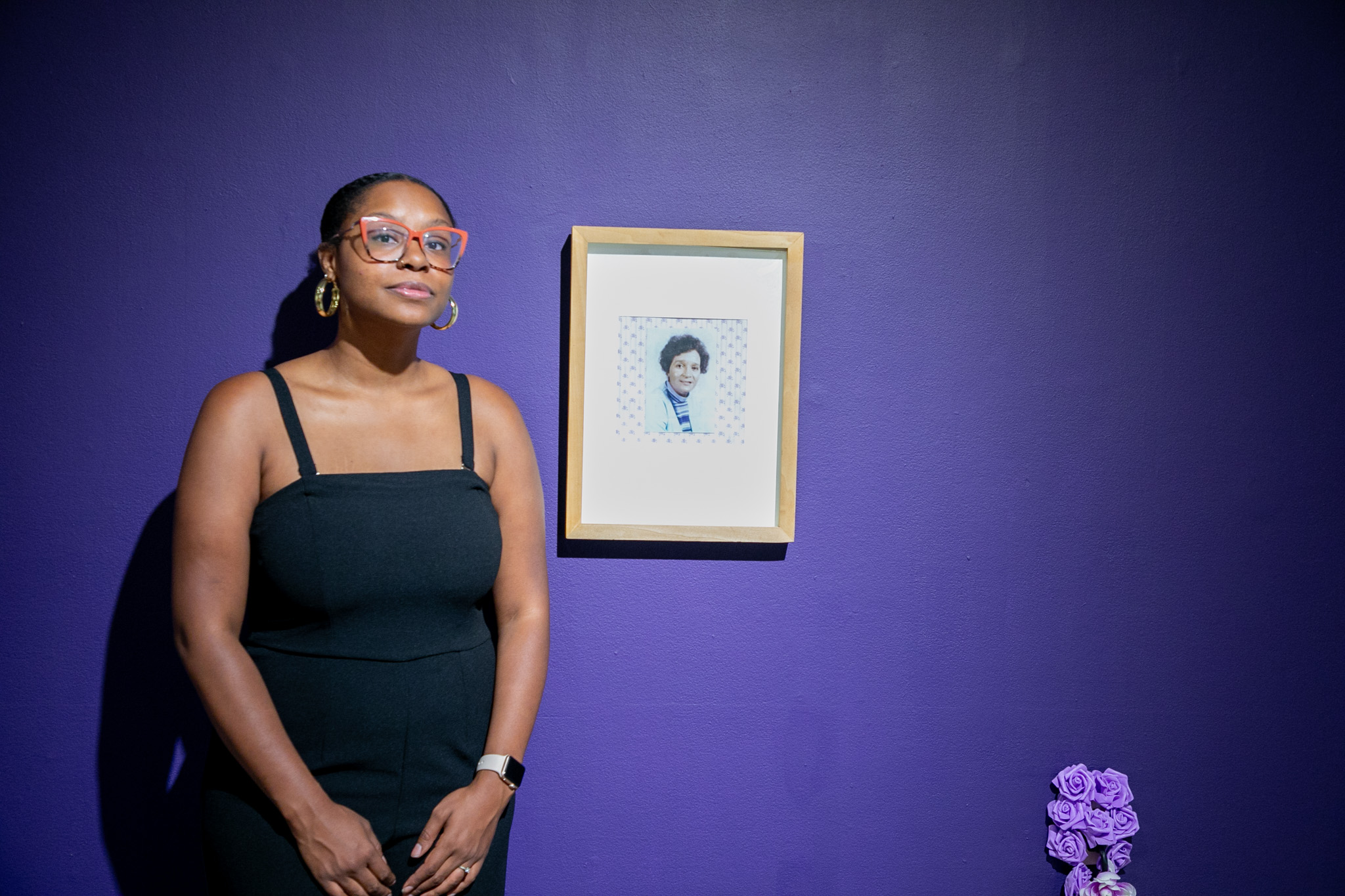 Ajanaé standing next to a photo of her great-grandmother included in her piece "Inheritance"