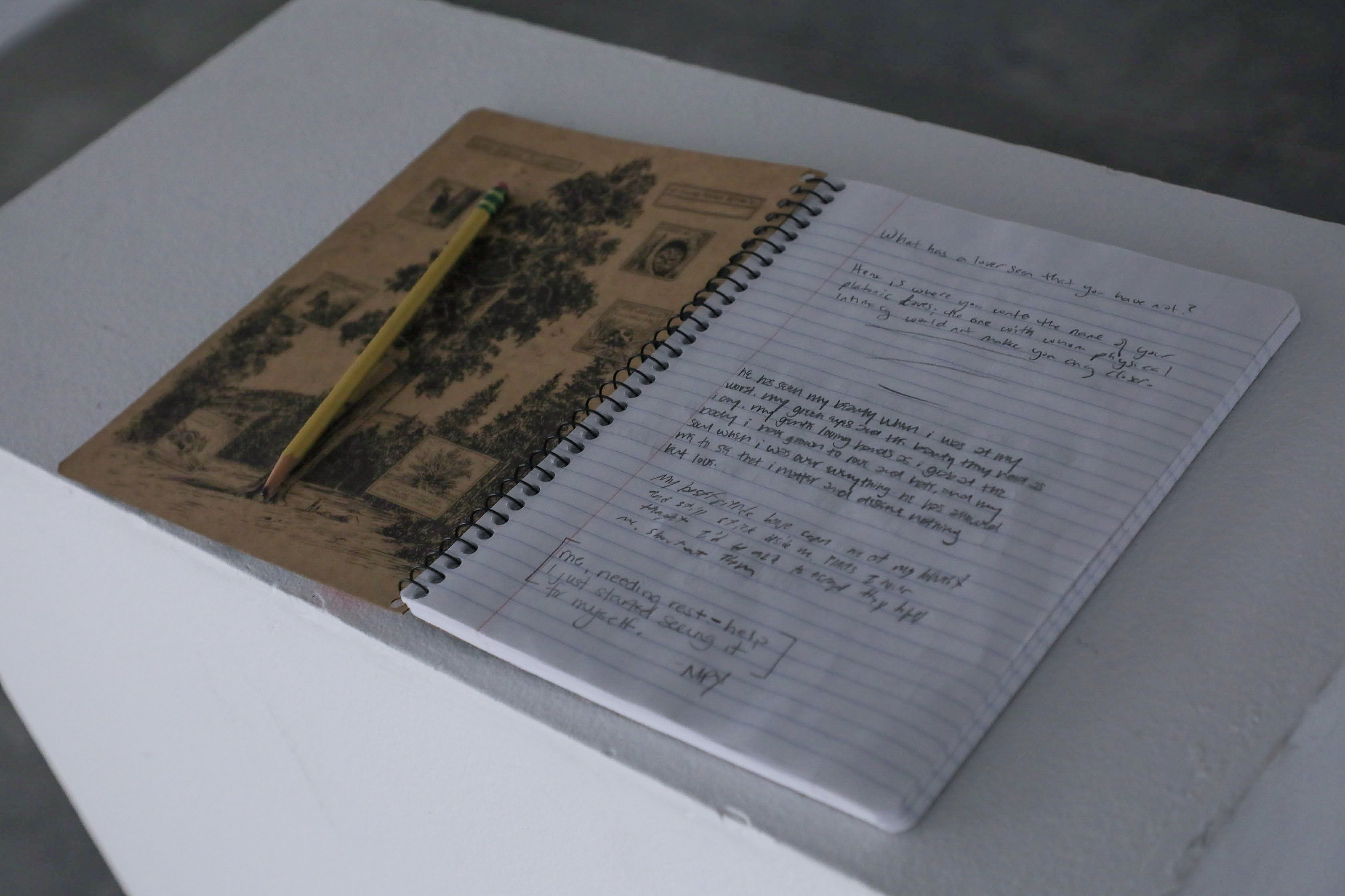 A white stand with a notebook and pencil for participants to write in. 