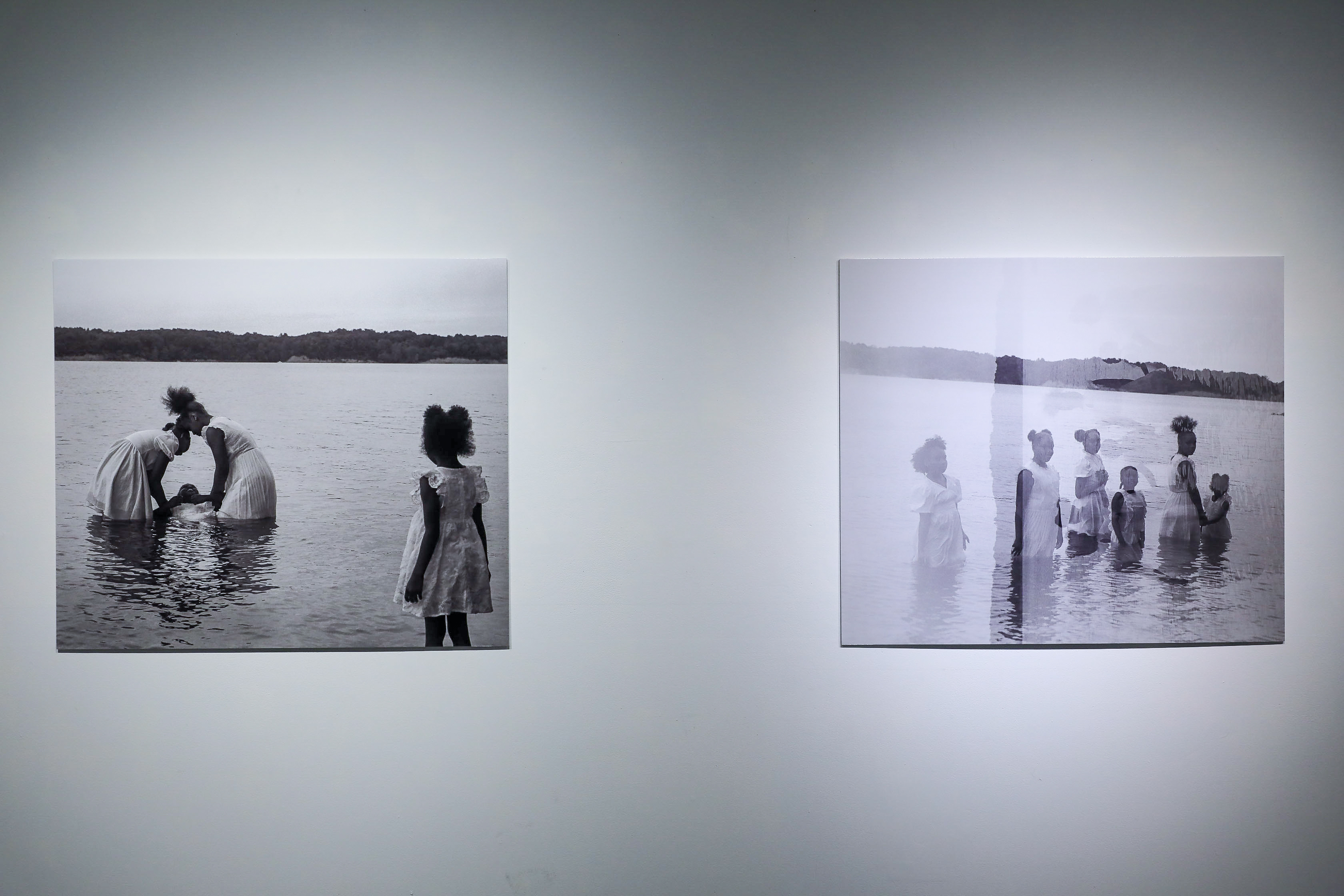 There are two black and white photos: the one of the left shows two black girls dressed in white in a lake baptizing a third while a fourth watches from the right. The one on the right shows six black girls dressed in white standing in a lake together with an alternate version of the photo overlayed on top.