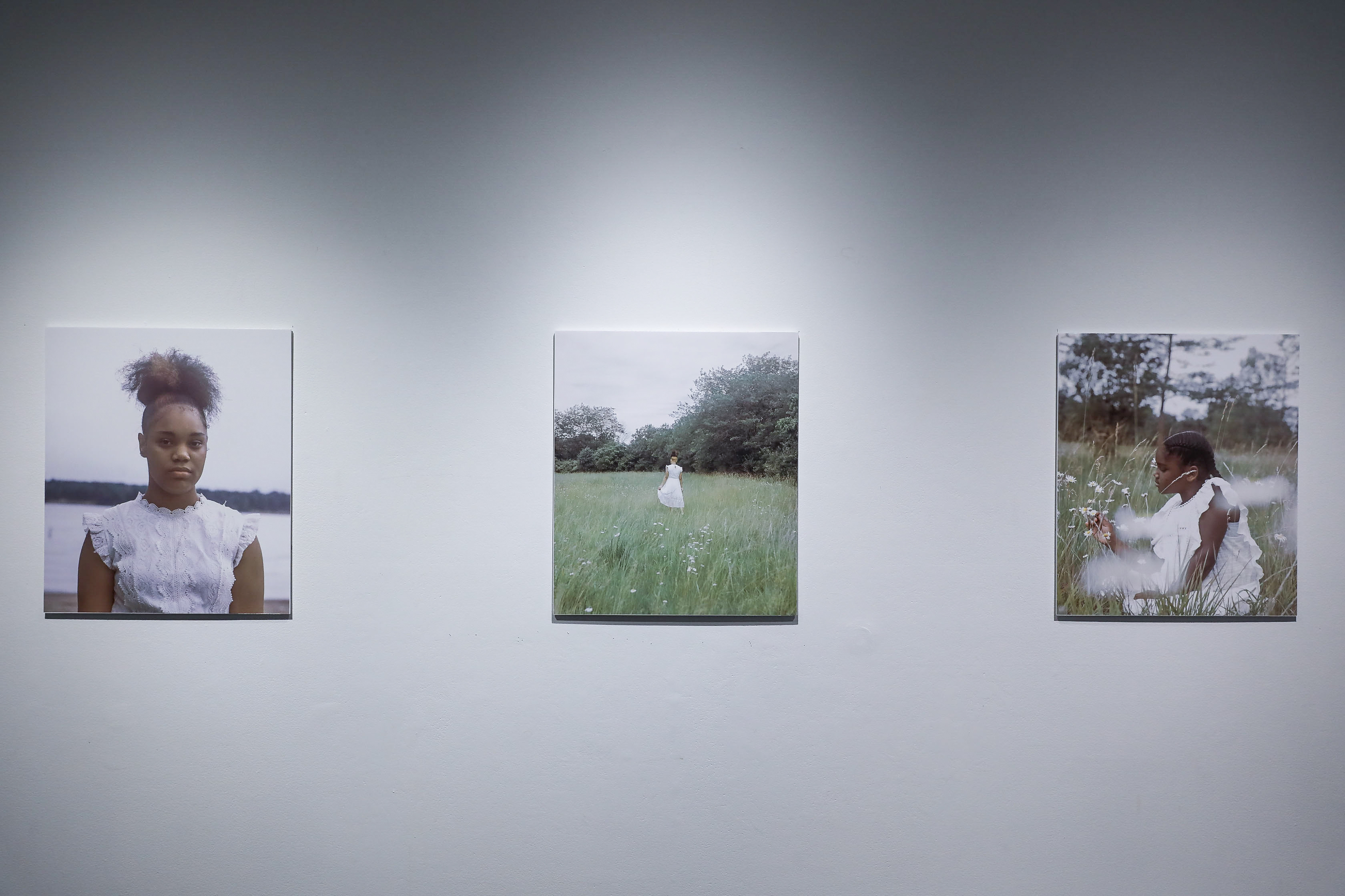 There are three color photos: the one on the left is a portrait of a black girl dressed in white. The middle is a wide shot of a black girl dressed in white standing in a field. The one on the right is a medium shot of a little black girl dressed in white playing with flowers in a field. 