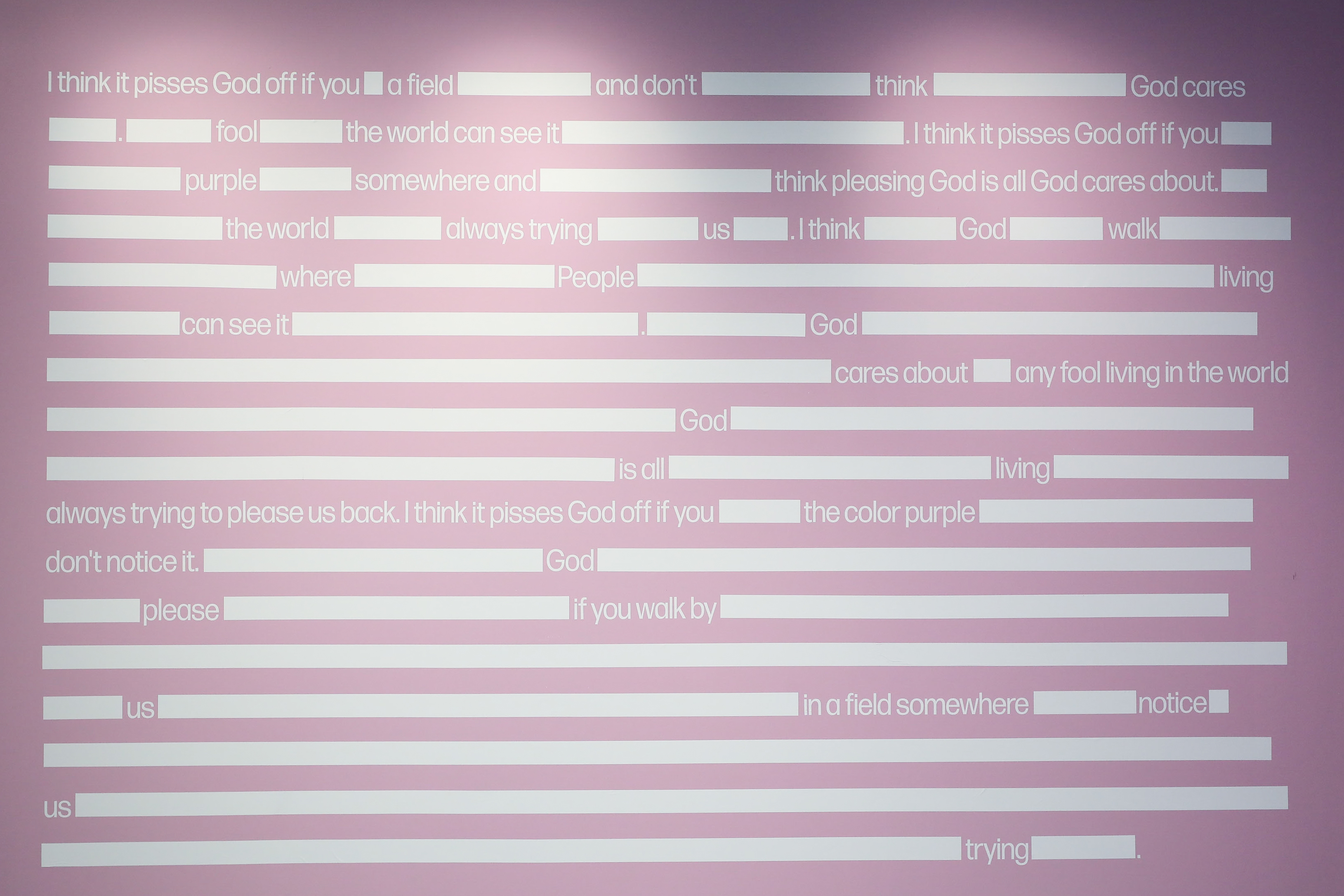 A quote from The Color Purple on a purple wall with words and sentences blocked out with white boxes.