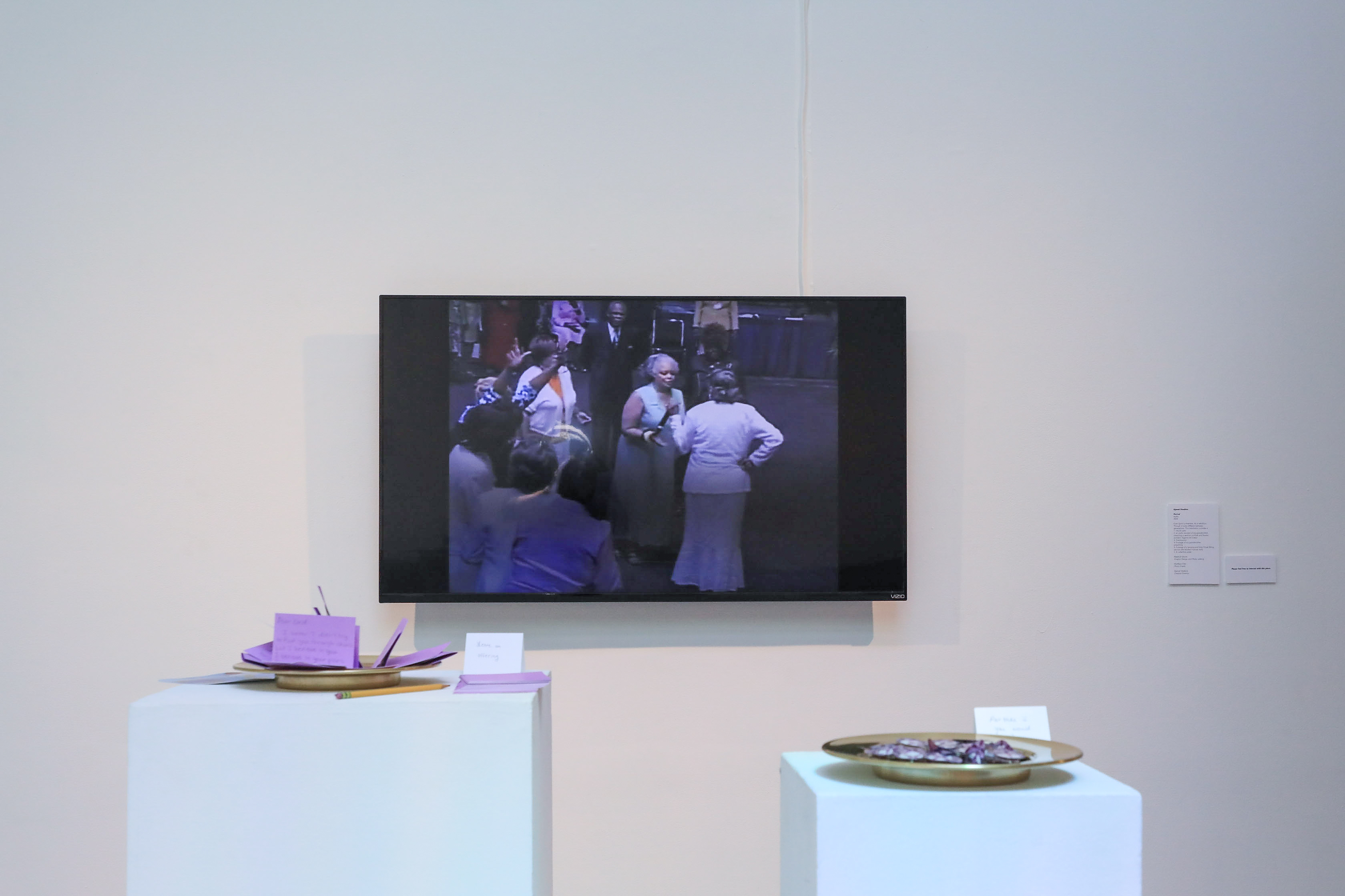 A TV with a video of a tarrying and Holy Ghost filling service with Mother Frances Kelly. In front of the TV are two columns with a collection plate and Communion.