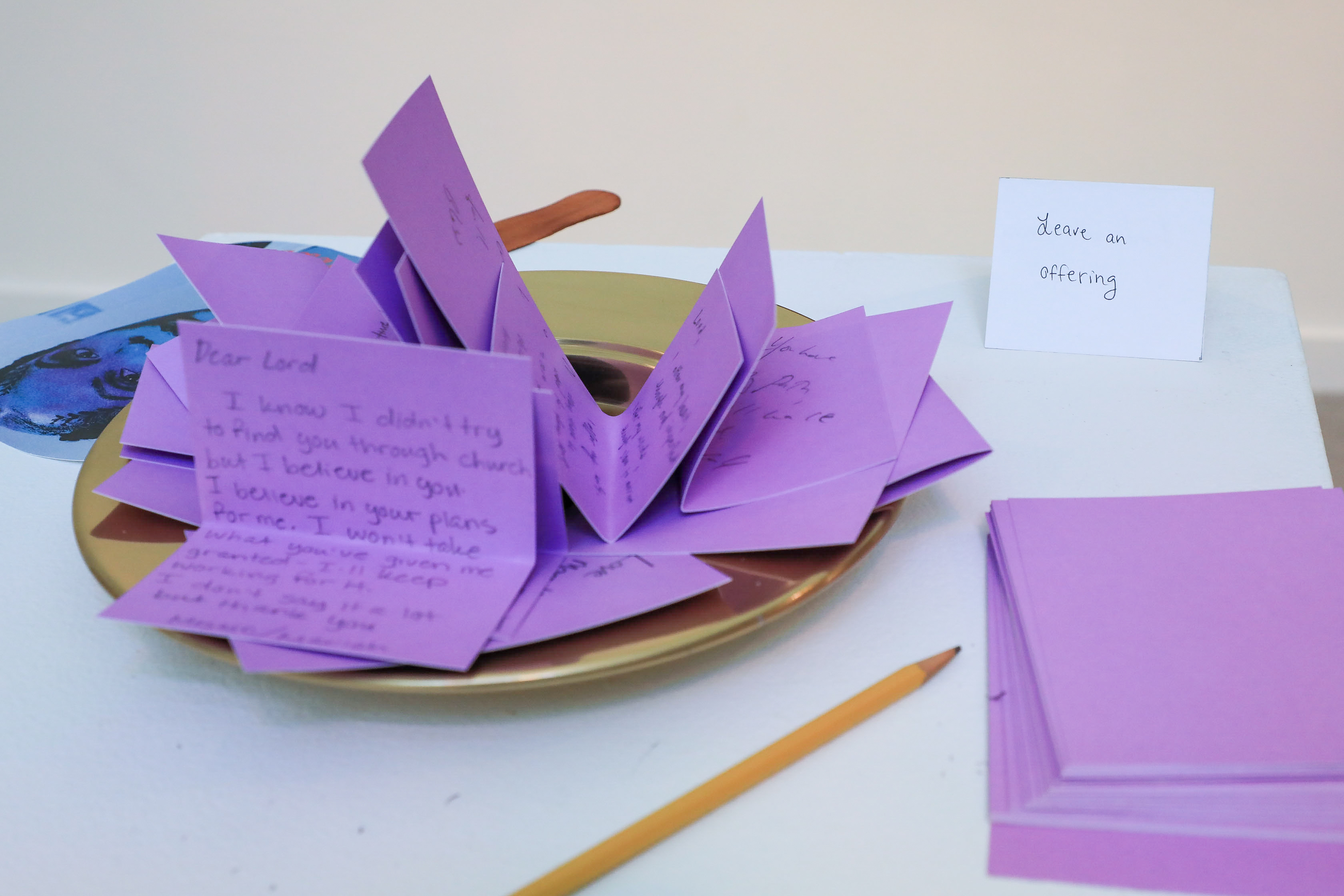 A collection plate with folded purple cards to leave offerings. 