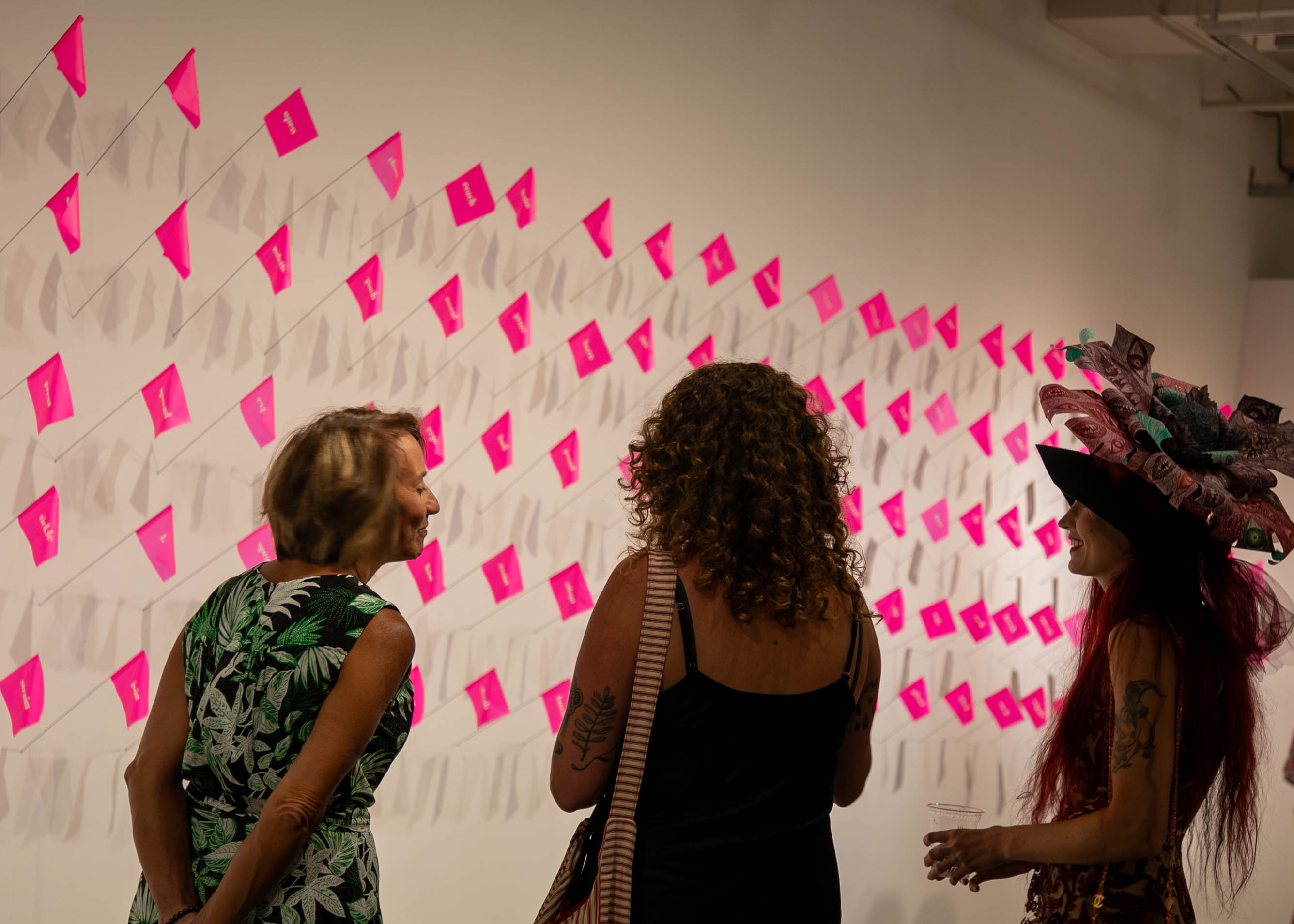 Guests and the artist viewing pink flags on the wall