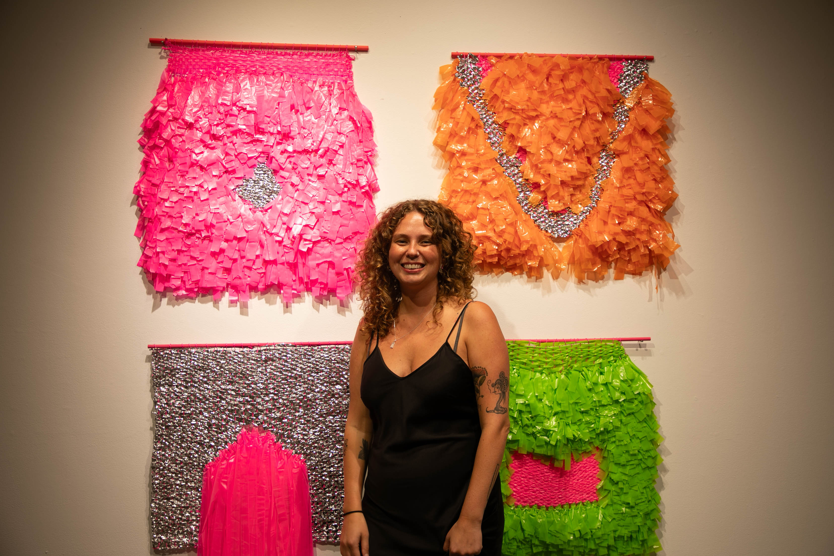 Alex in front of her emergency blankets repurposed into colorful weavings