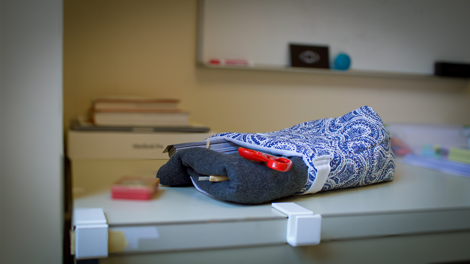 A cloth pouch in blue and white holding scissors and other crafting supplies