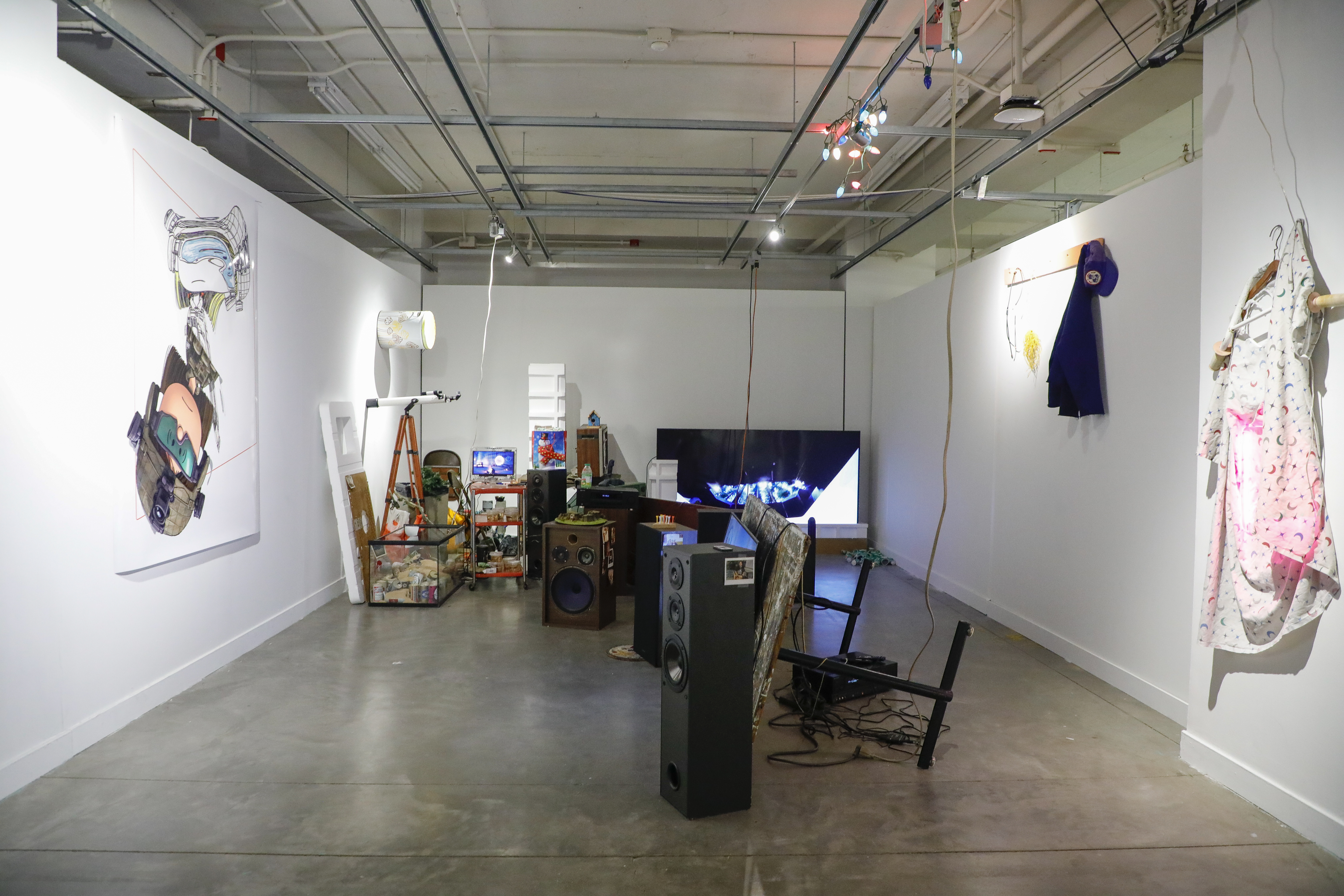 gallery filled with found objects, including a TV on the floor, steroes, and a fish tank filled with sand