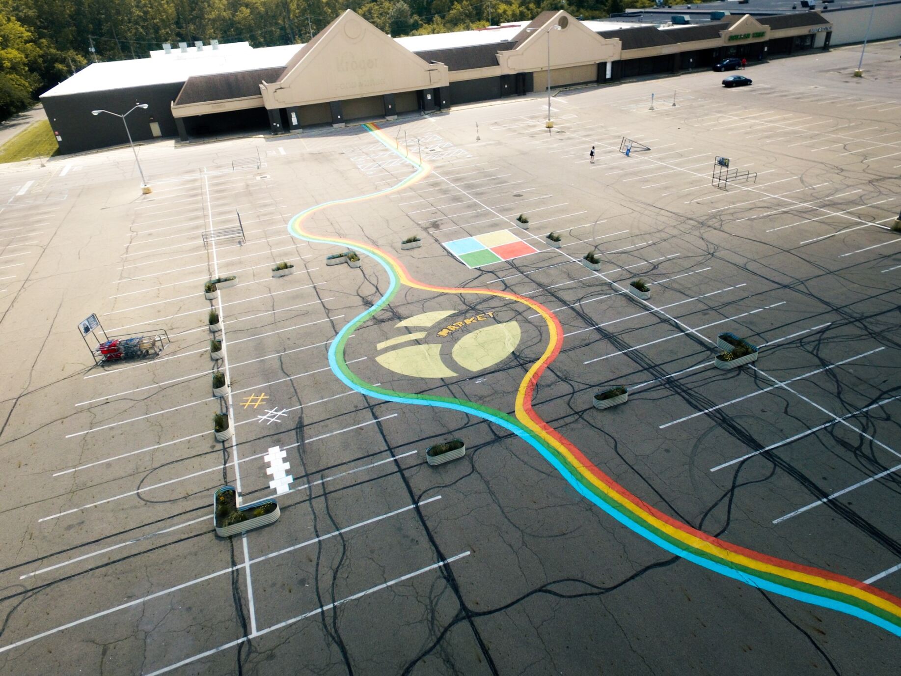 a rainbow design painted on the parking lot of, four square court, and text that reads "market"
