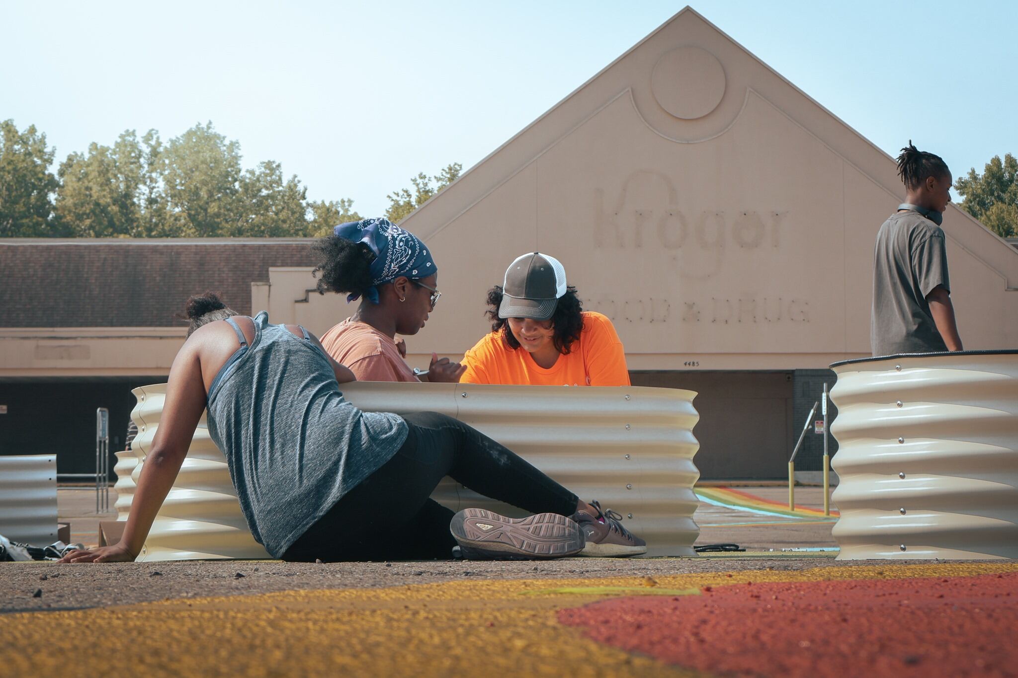 four students working on a flower box outside a Kroger being renovated