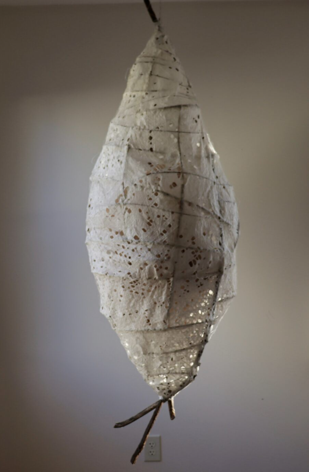 A large sculpture of a cocoon made out of paper and wood