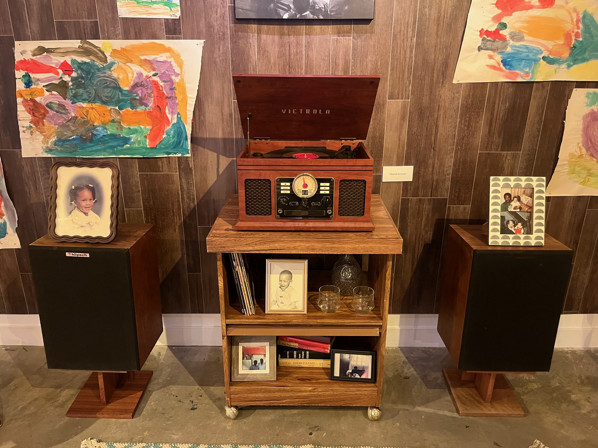 A vintage Victrola record player on top of a rolling side table, with a floor speaker on each side of the table.