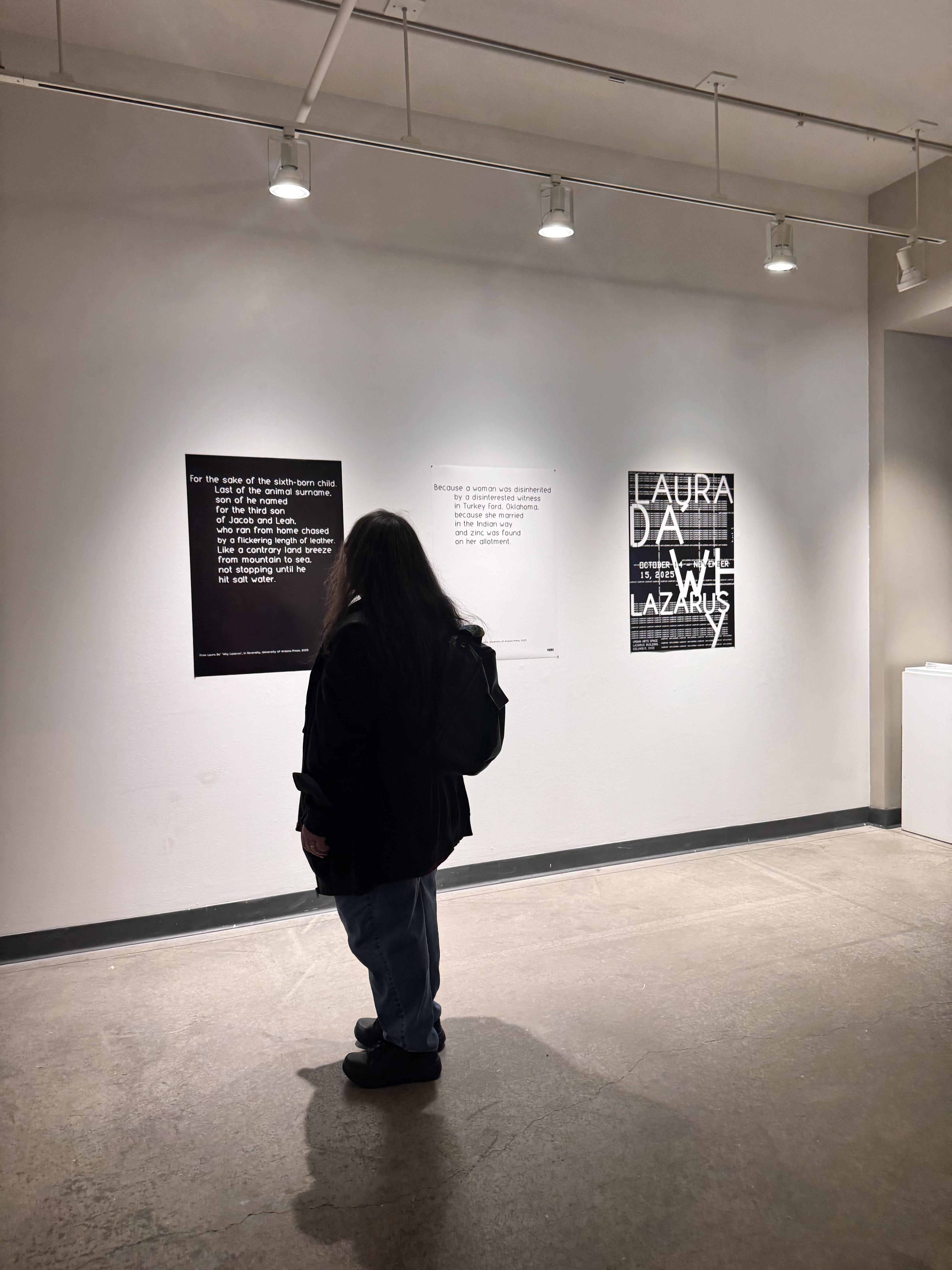 visitor looking at posters of Laura's poem on the gallery wall