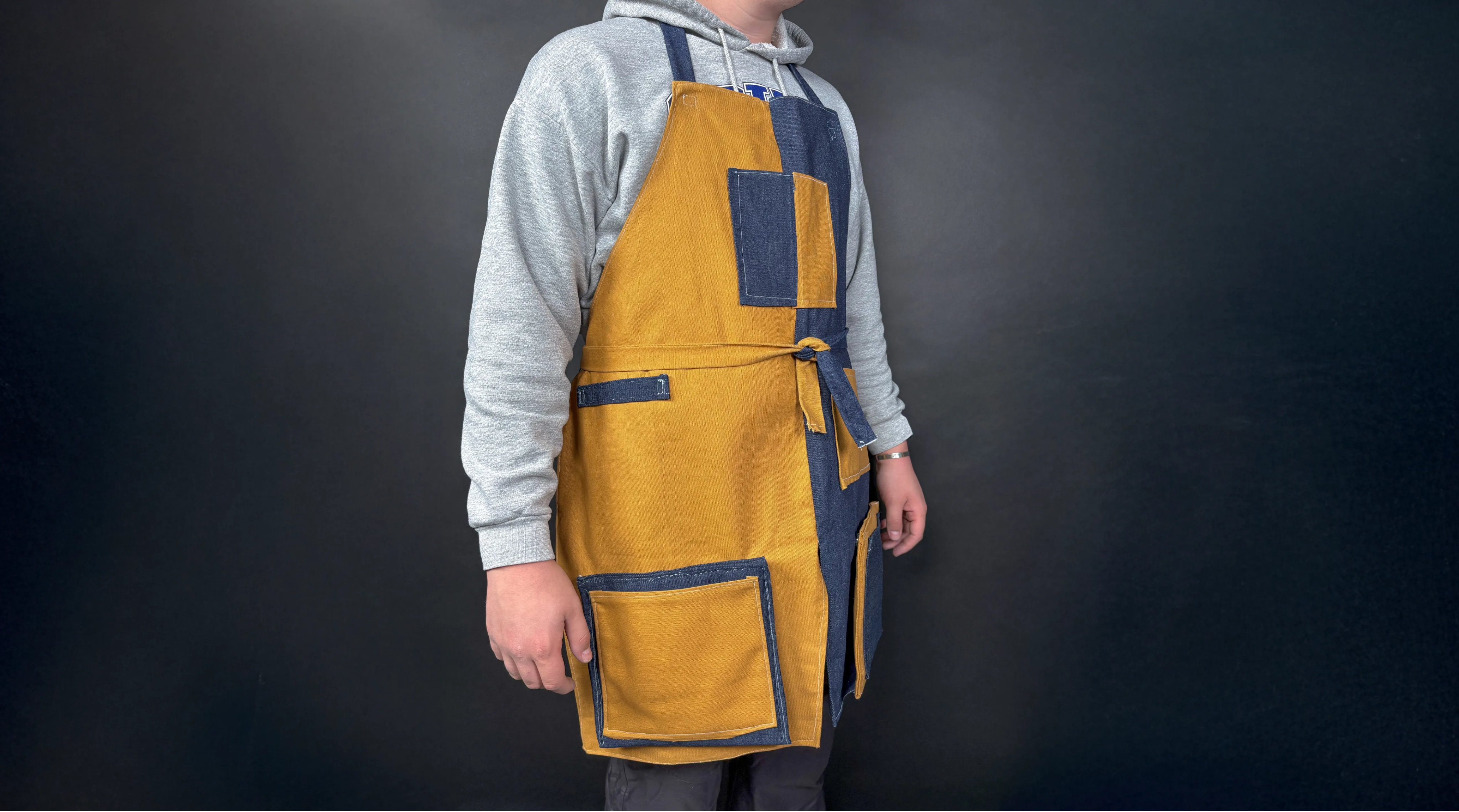 person wearing a yellow and blue apron with pockets