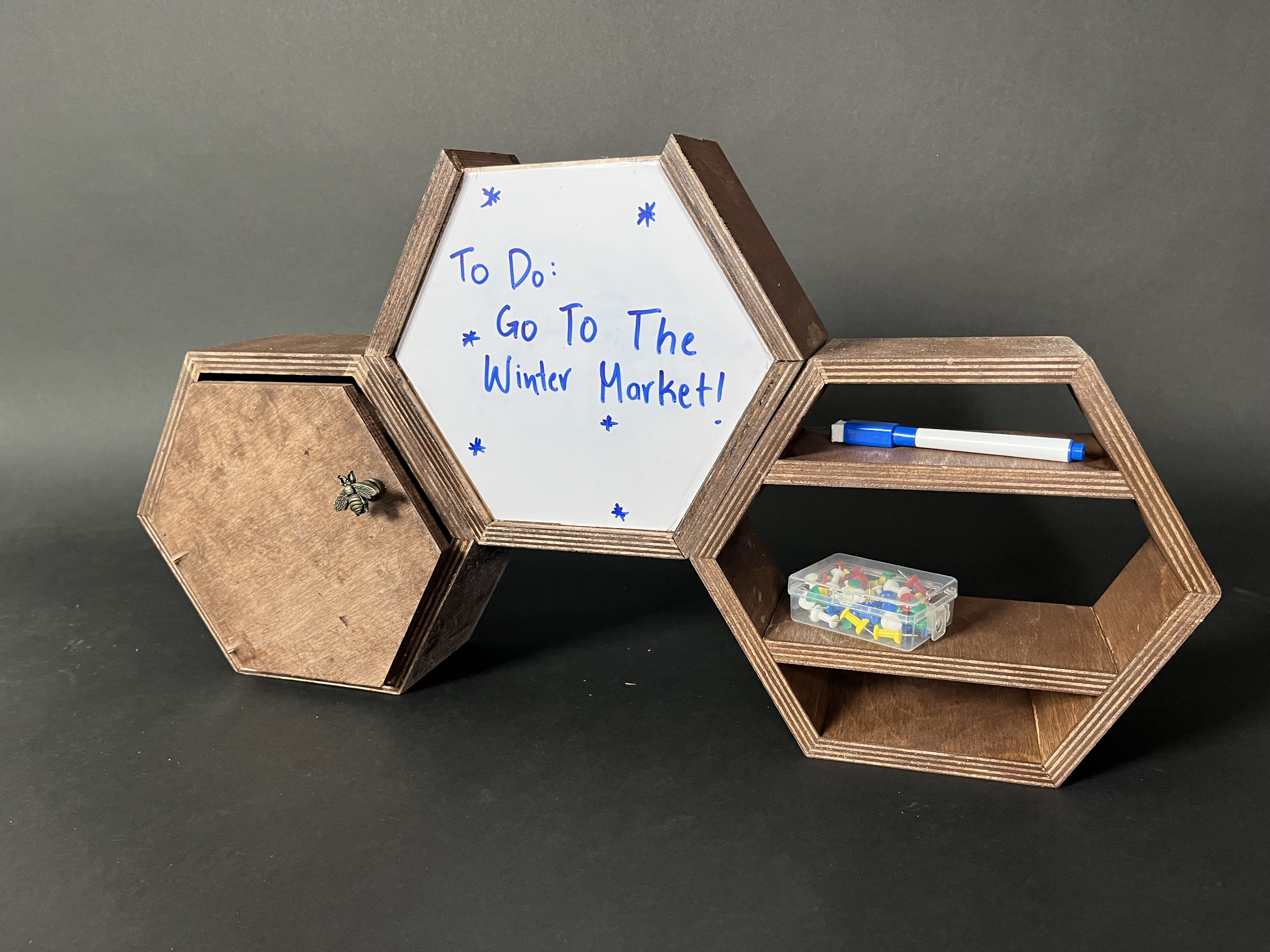 there hexagonal desk containers with a dry erase board that says go to the winter market