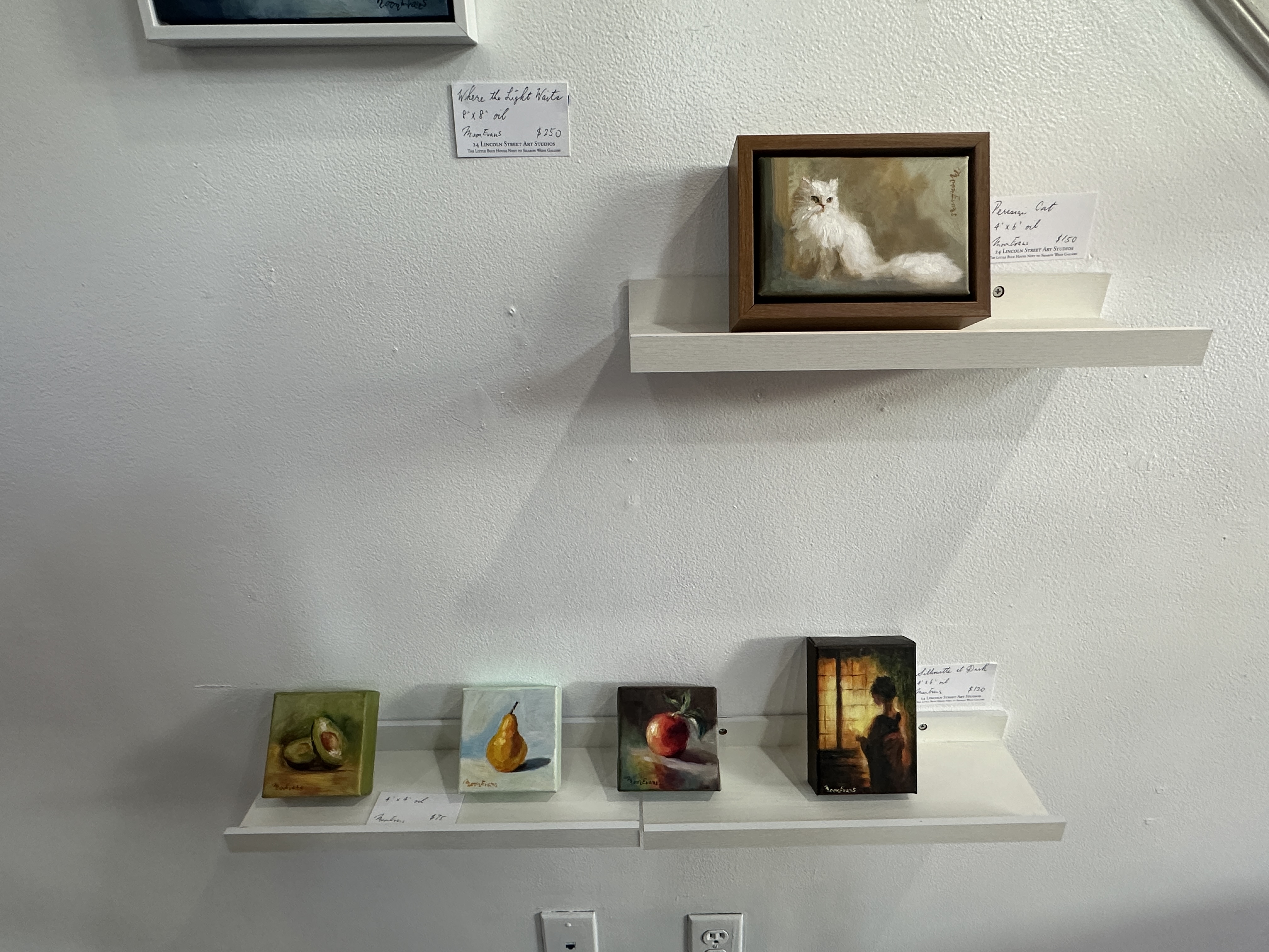 small paintings of fruits and a white cat