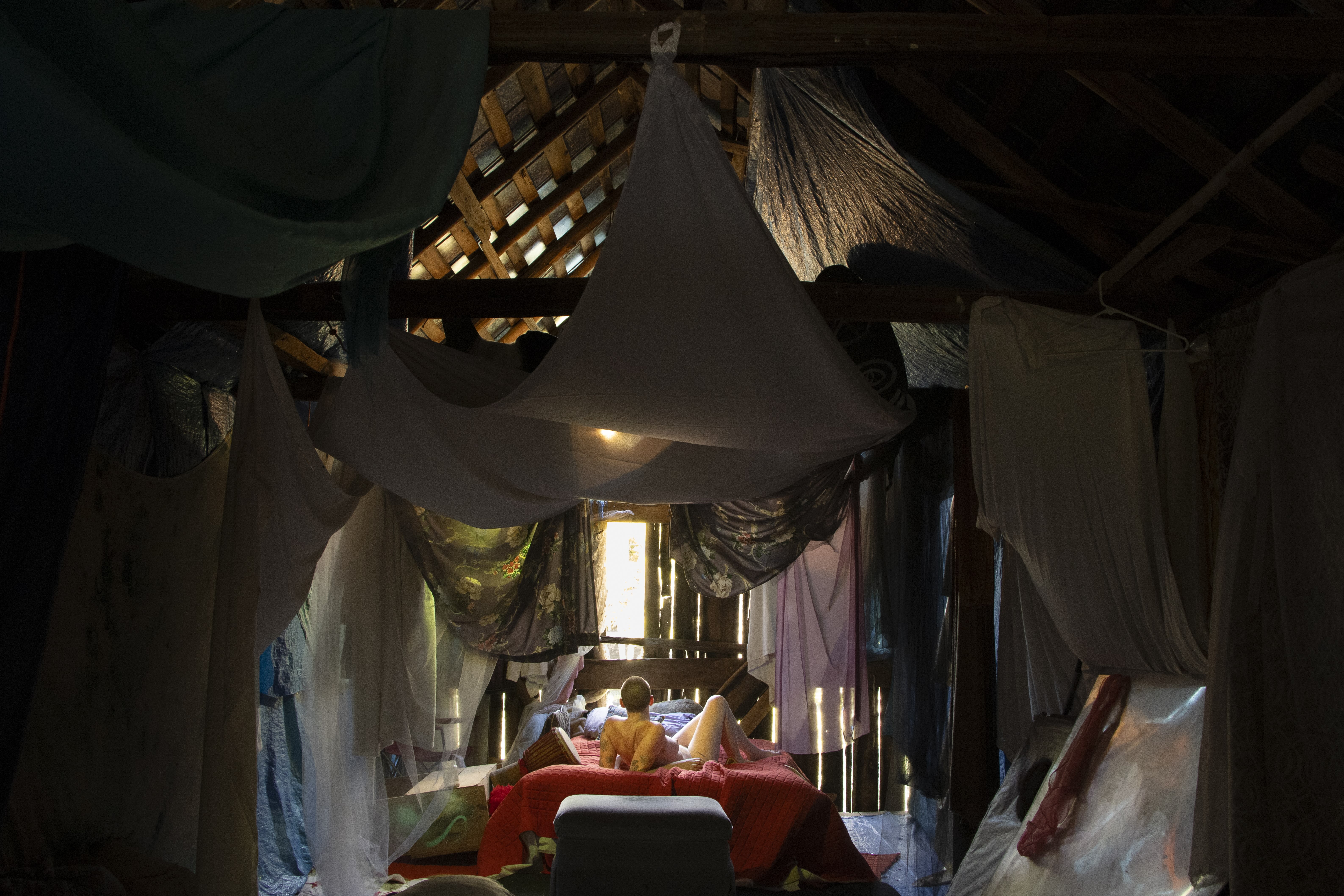 person lying in a bed with cloth draped across the ceiling