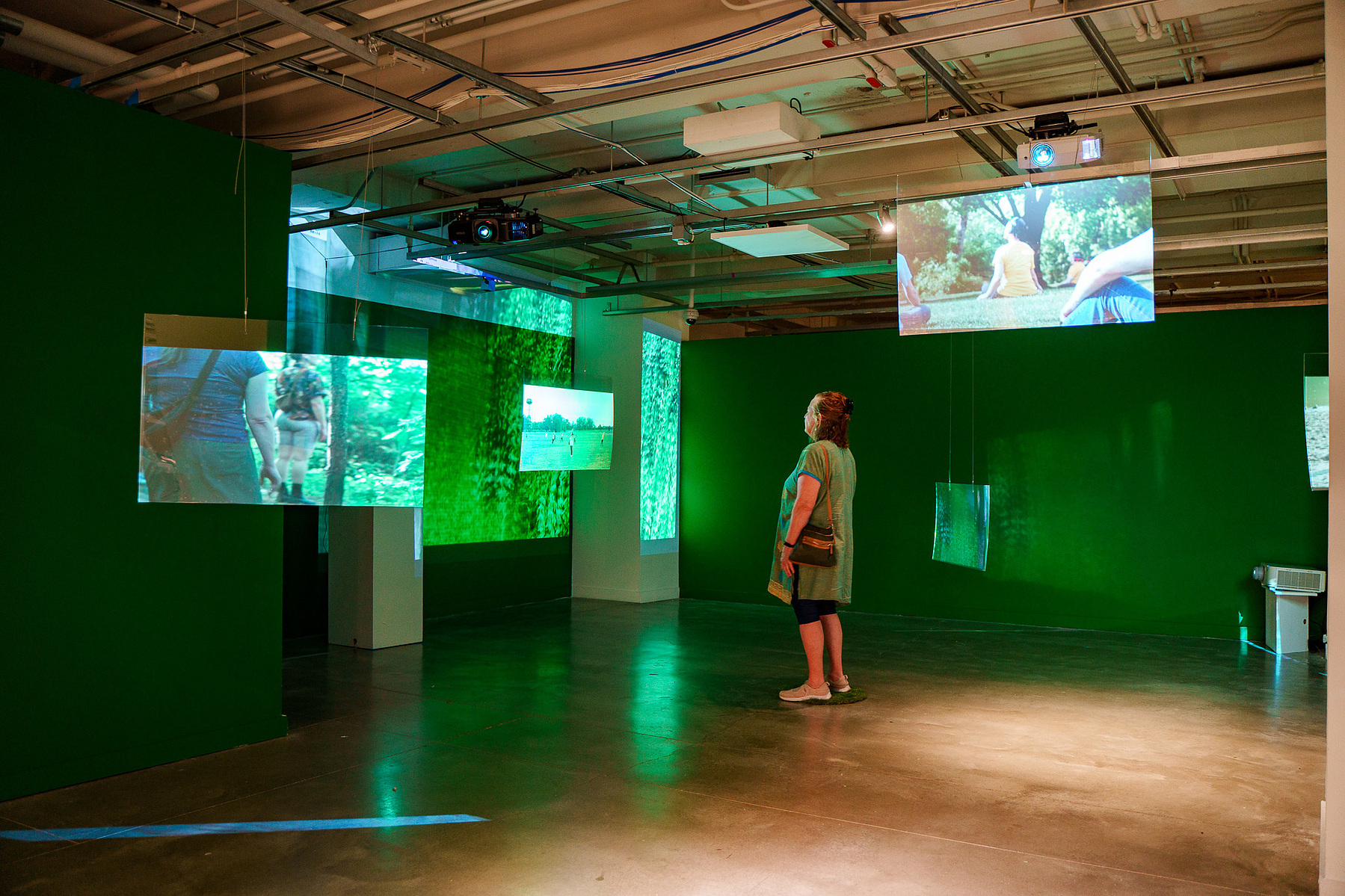 visitor standing in the gallery with screens showing the movement performances at parks