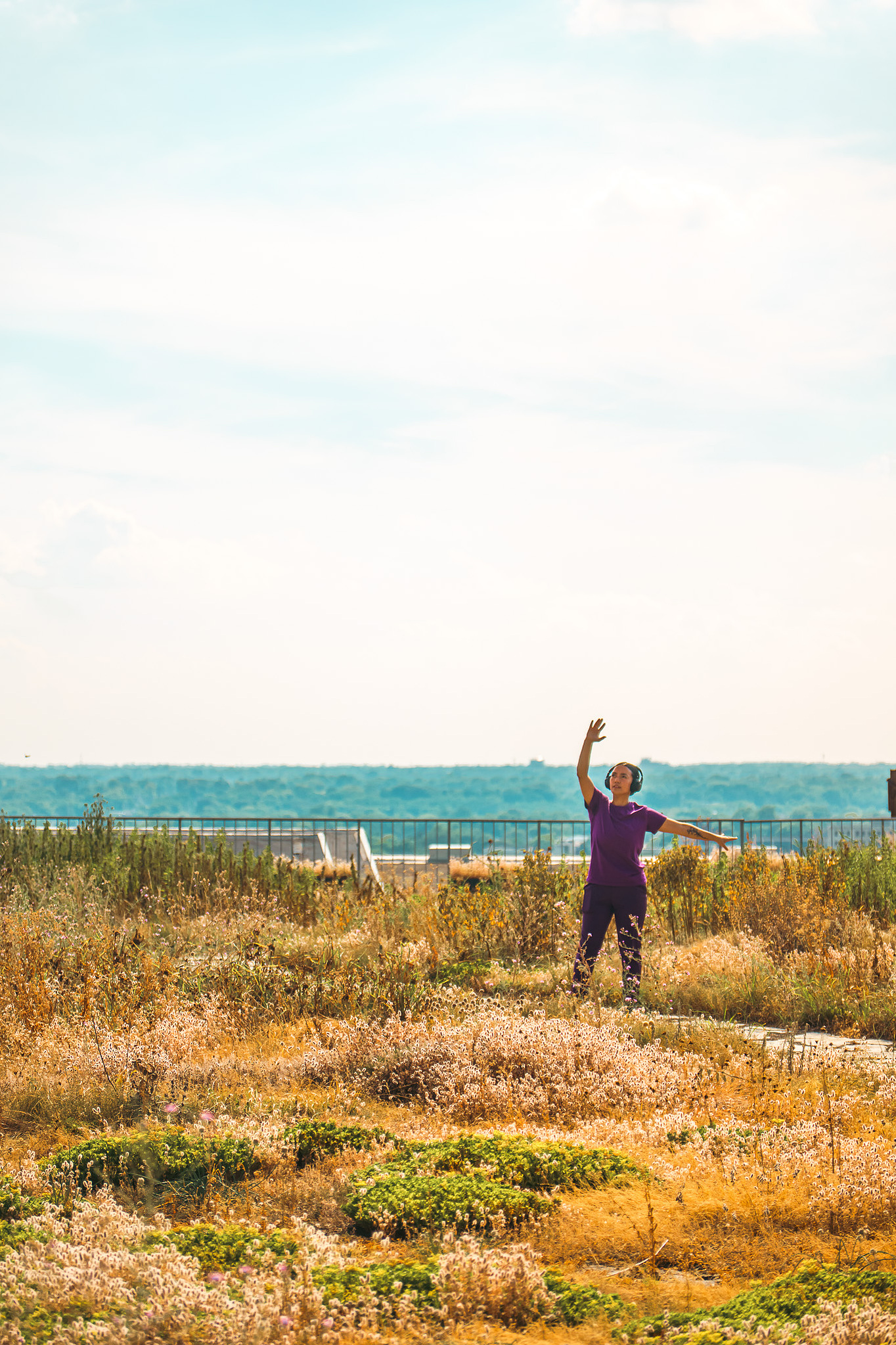 person with arms toward the sky on the rooftop garden