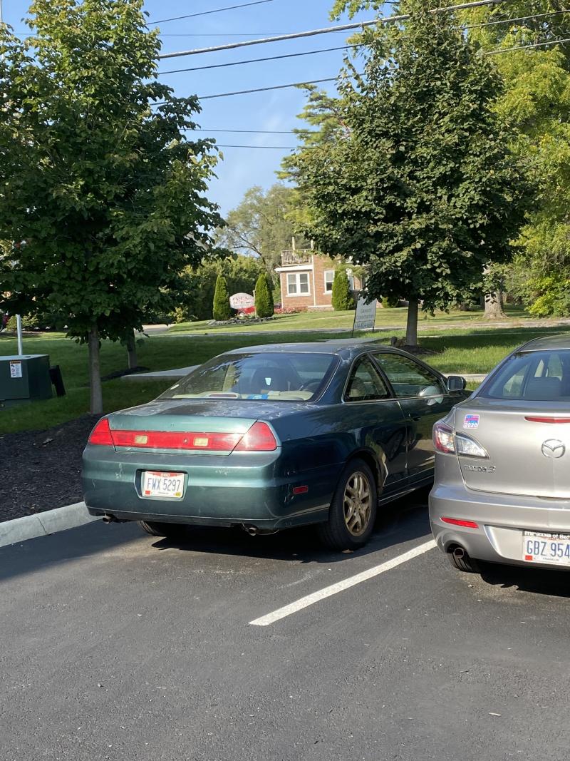 green car and silver car in parking lot