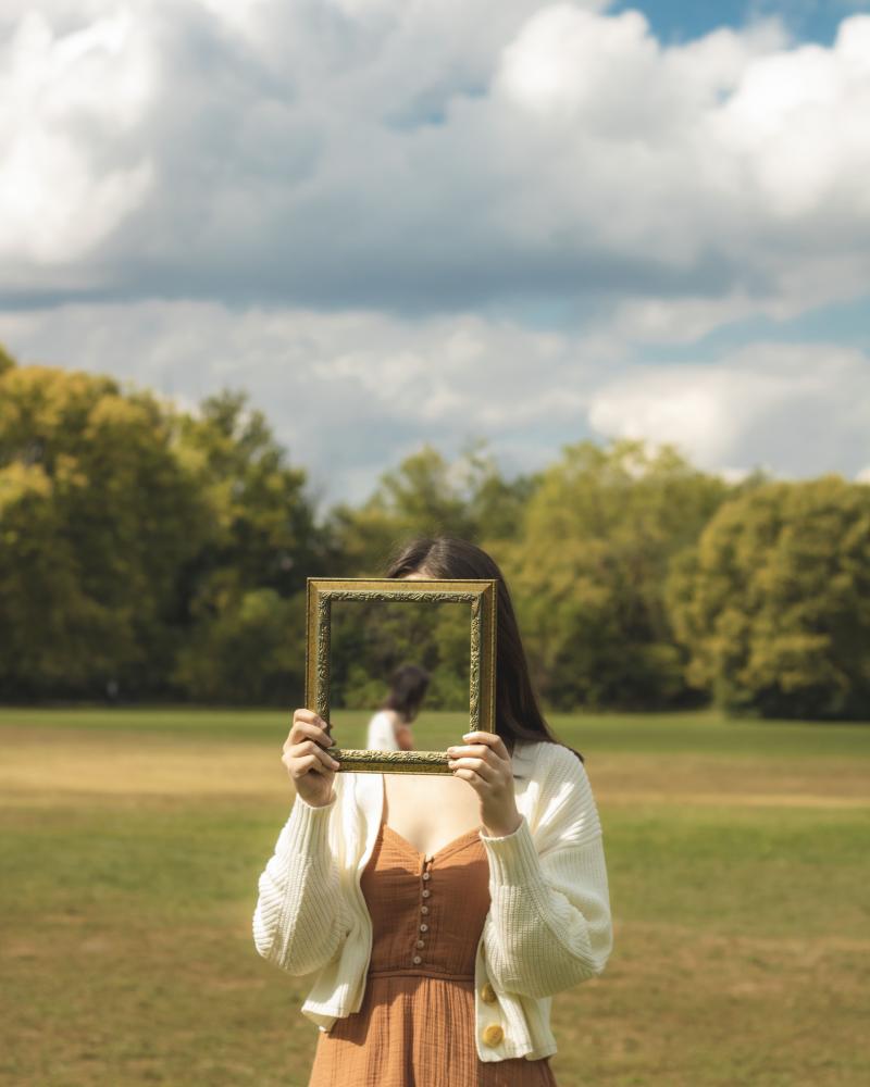Woman holding frame in outdoor green field