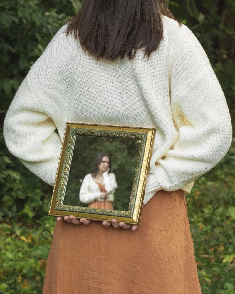 Woman holding frame in outdoor green field