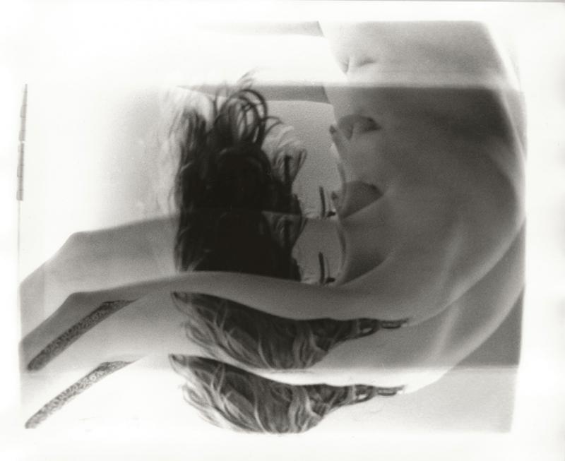 A black-and-white photo of an upside-down shirtless person with head bent