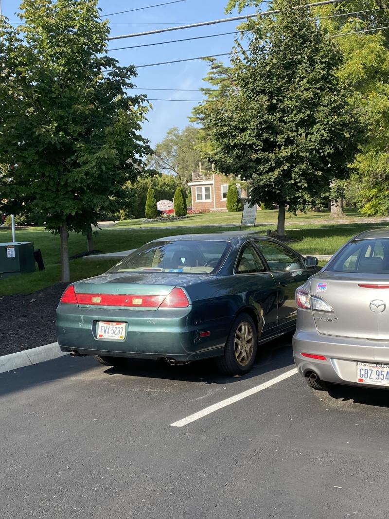 green car and silver car in parking lot