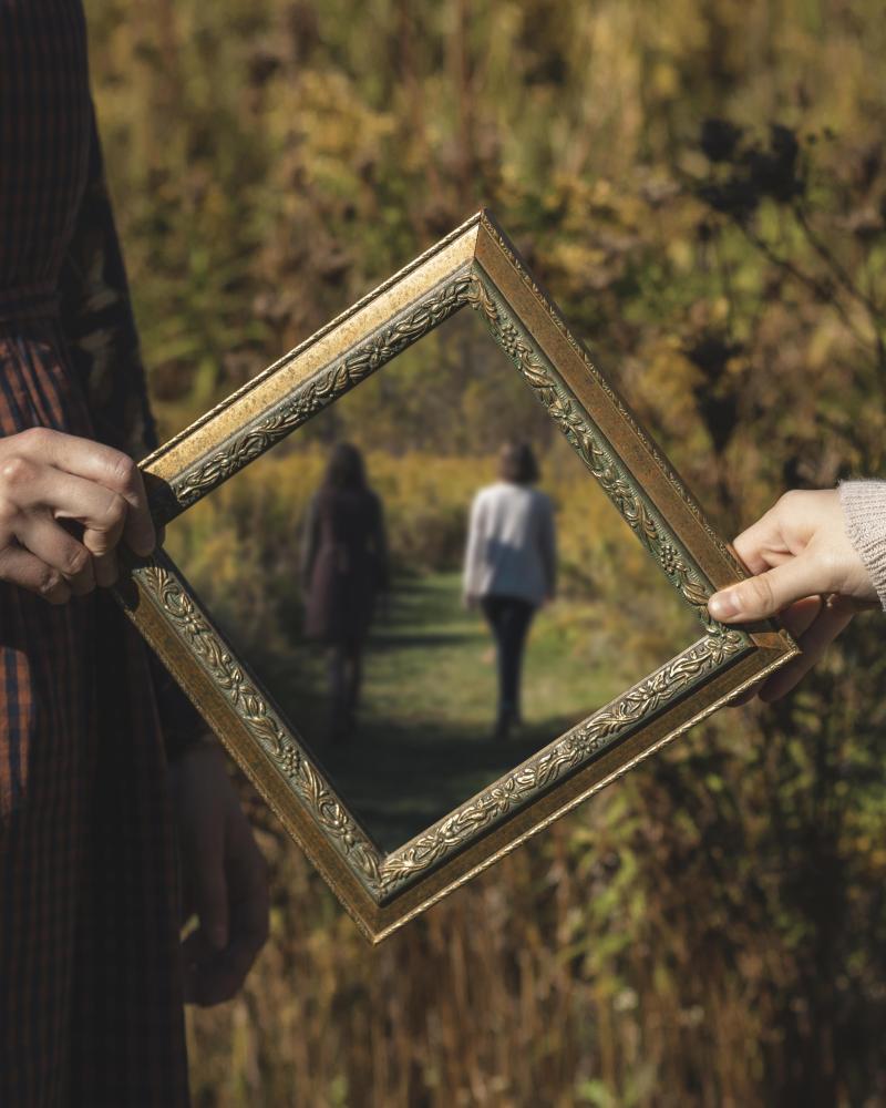 Woman holding frame in outdoor green field