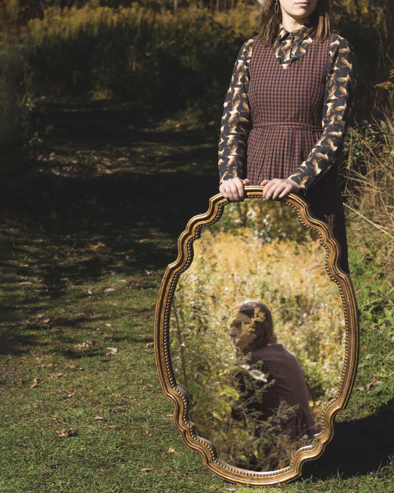 Woman holding frame in outdoor green field