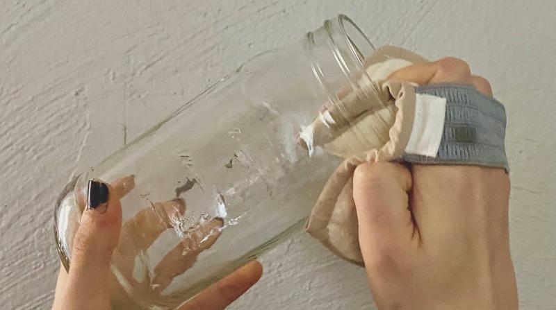 A model uses a Scrubbit to clean a glass jar.