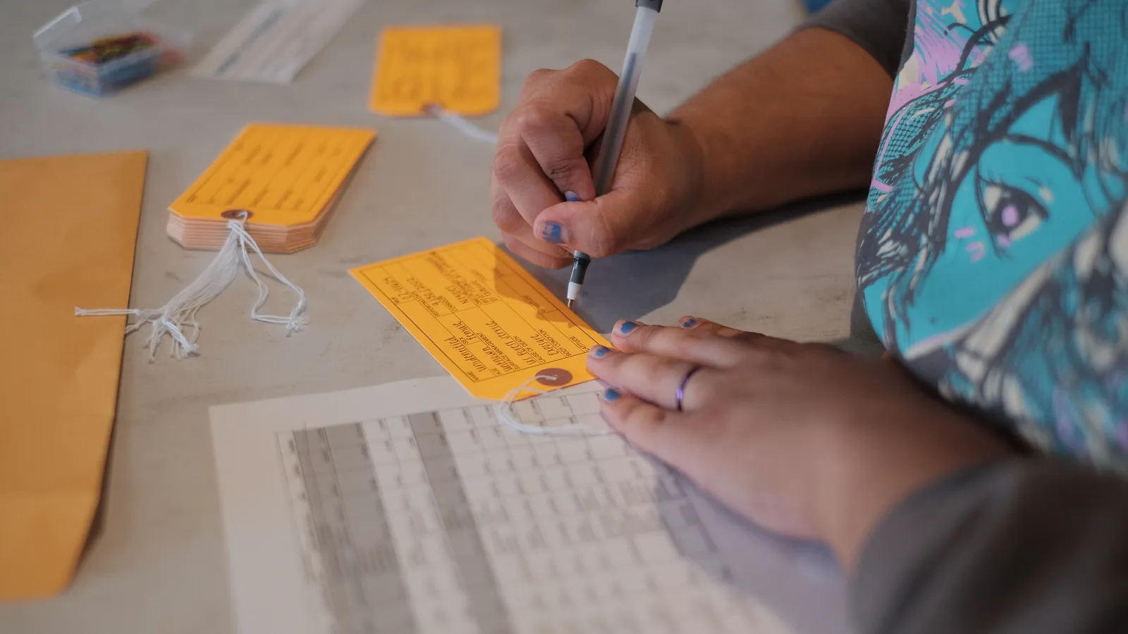 a person writing on an orange tag, on an office desk