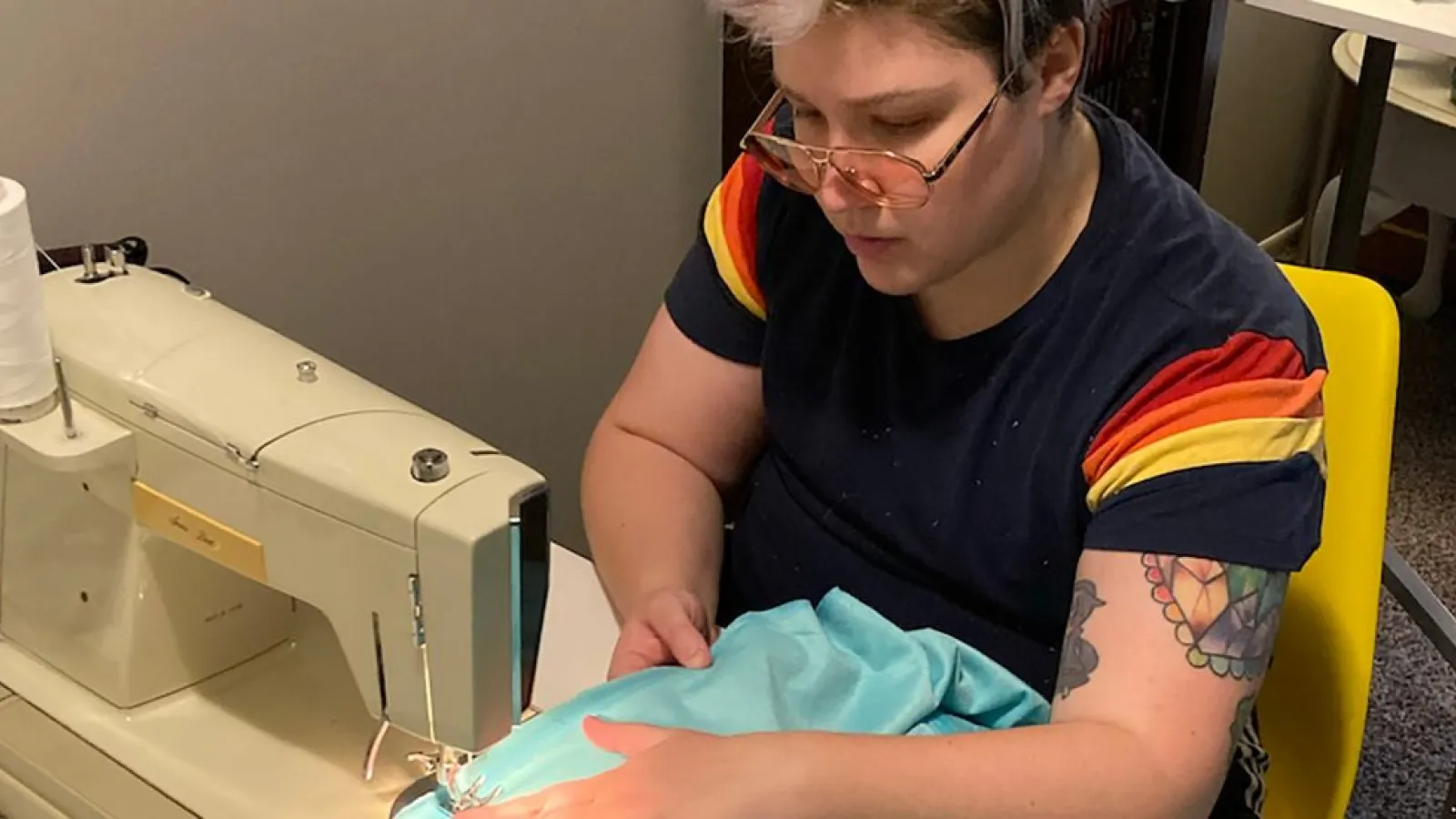Mitch Vicieux using a sewing machine while working on their art piece