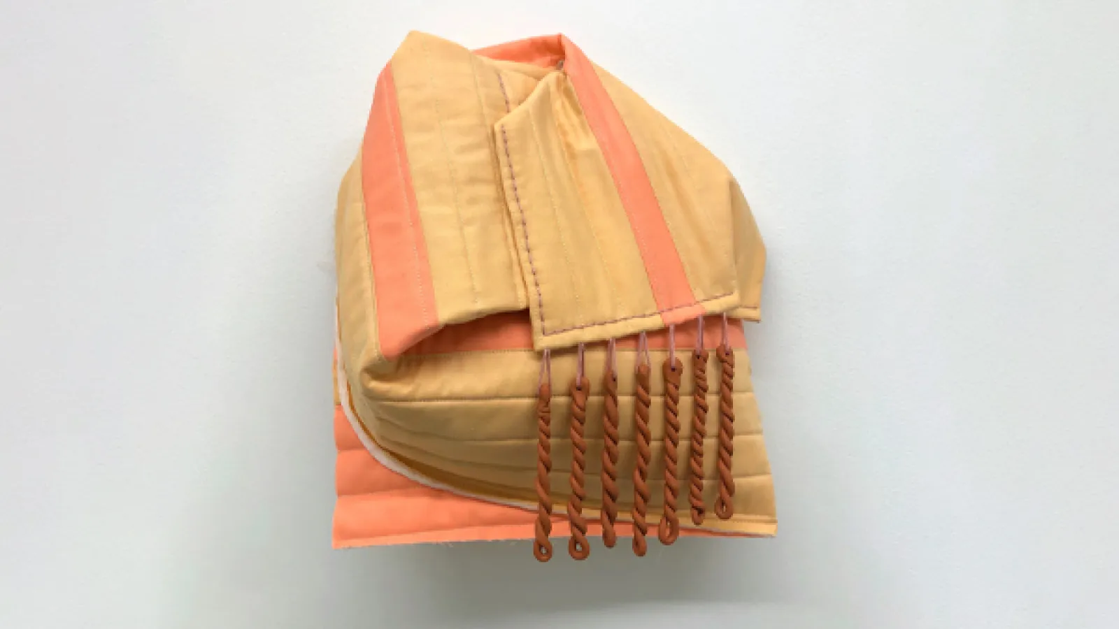 sculpture made from terra-cotta and cotton, a orange fabric is warped around a spherical object