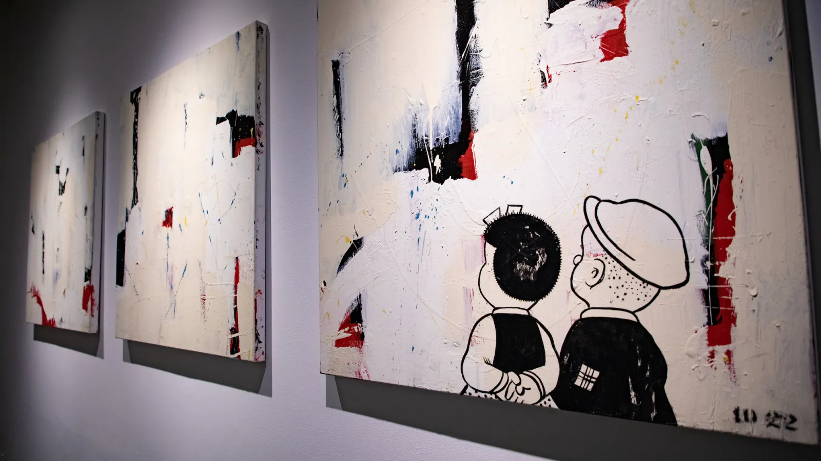 3 paintings with 2 cartoon characters looking at the canvases 
