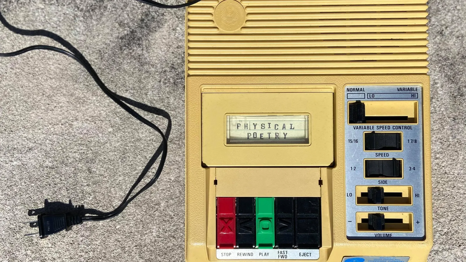 old fashion yellow recorder with a wire sitting on a grey floor 