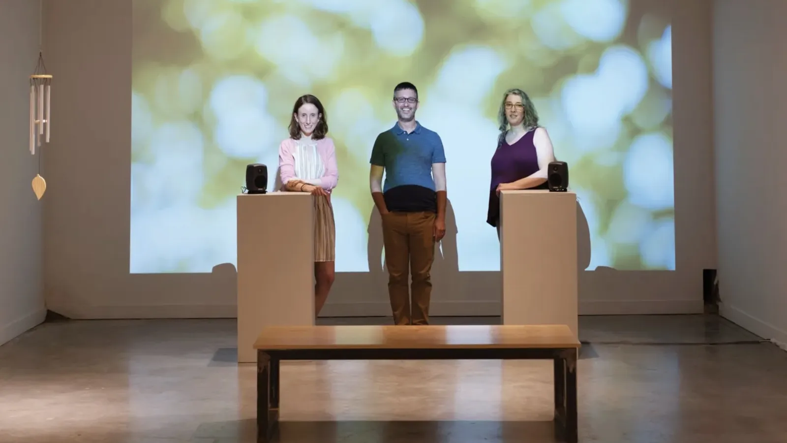 Three people standing in front of a green projected image