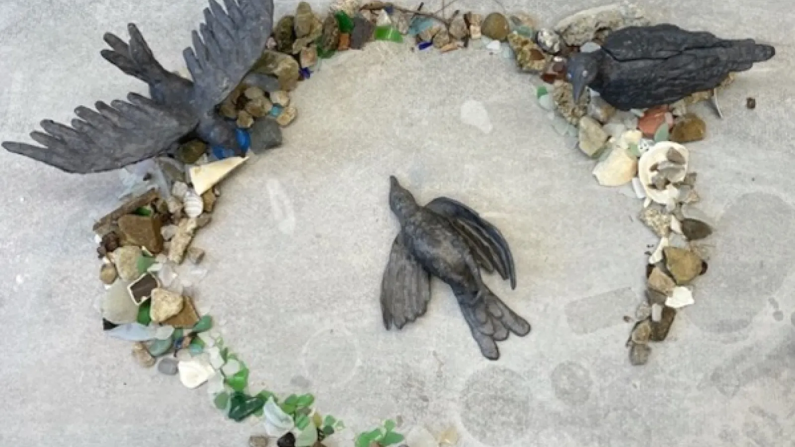 A sculpture of three birds in a ring of rocks