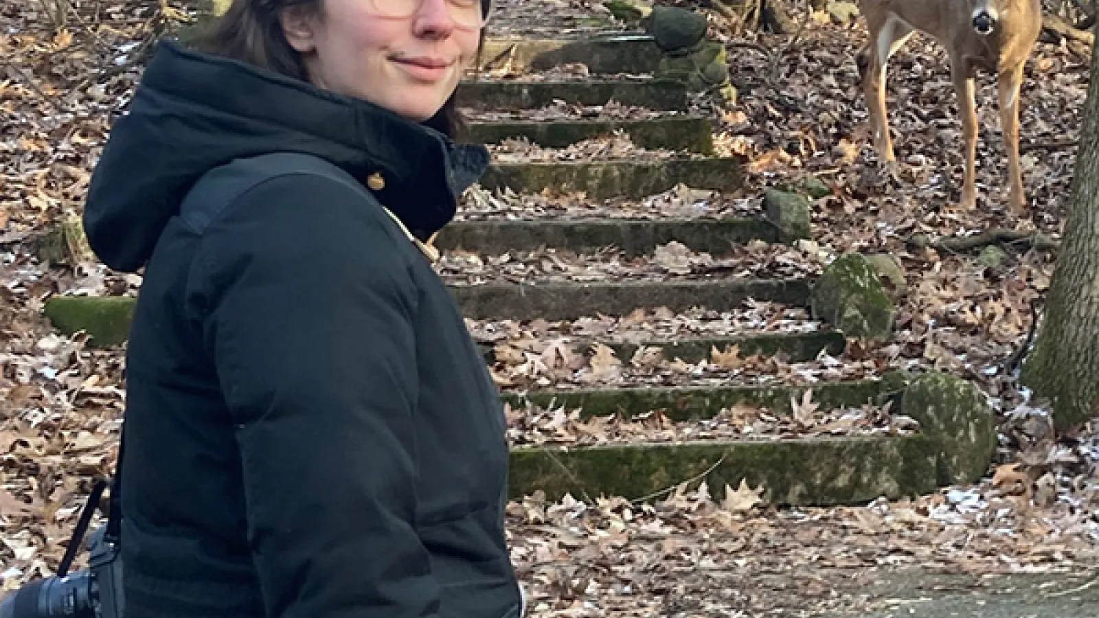 Julia in a photo with her camera and a deer