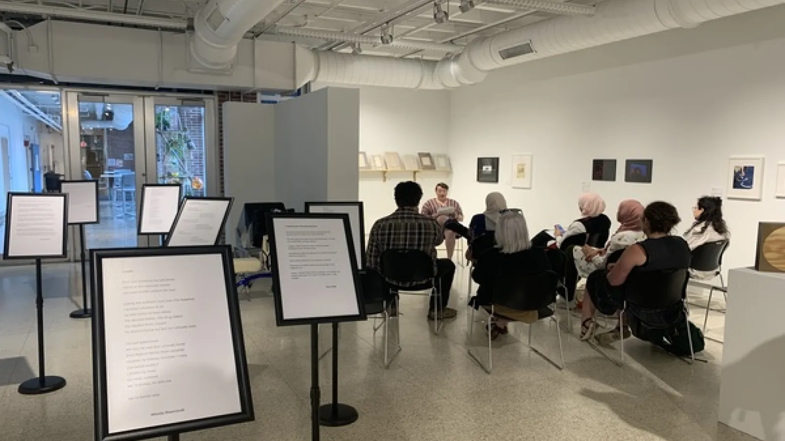 Visitors at Hopkins Hall Gallery listening to the poetry reading with the stands featuring poems in the foregorund