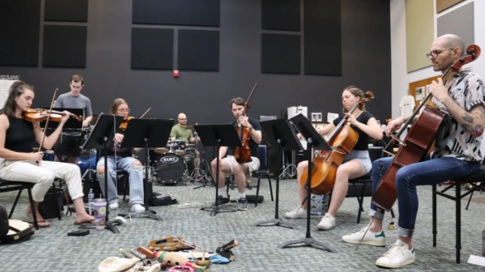 A photo of 7 musicians playing classical instruments in a practice room.