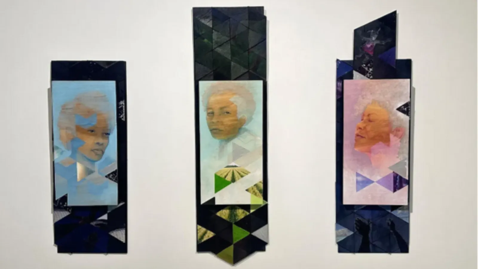 A photo of three portraits painted in light colors, primarily blue, green, and purple, hanging on the wall.